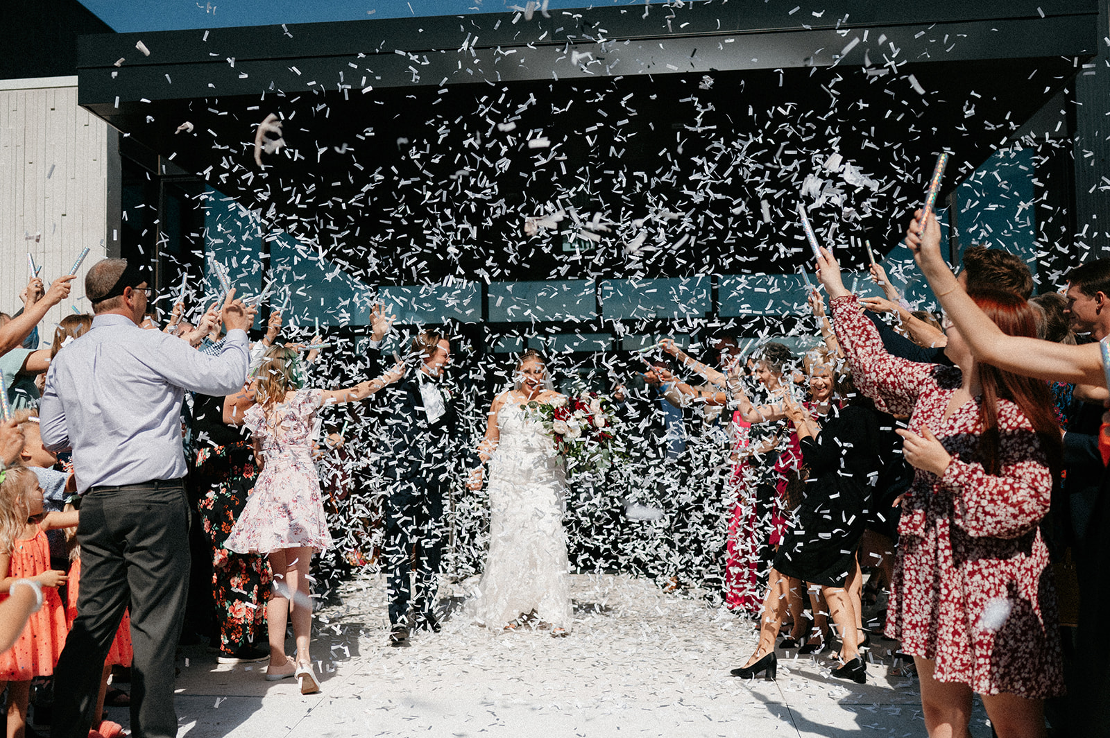 A couple walks out from their wedding ceremony to a confetti blizzard.
