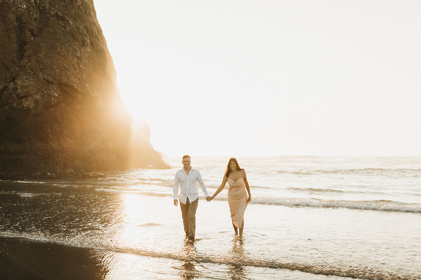 couple holding hands and walking on the shore during golden hour 