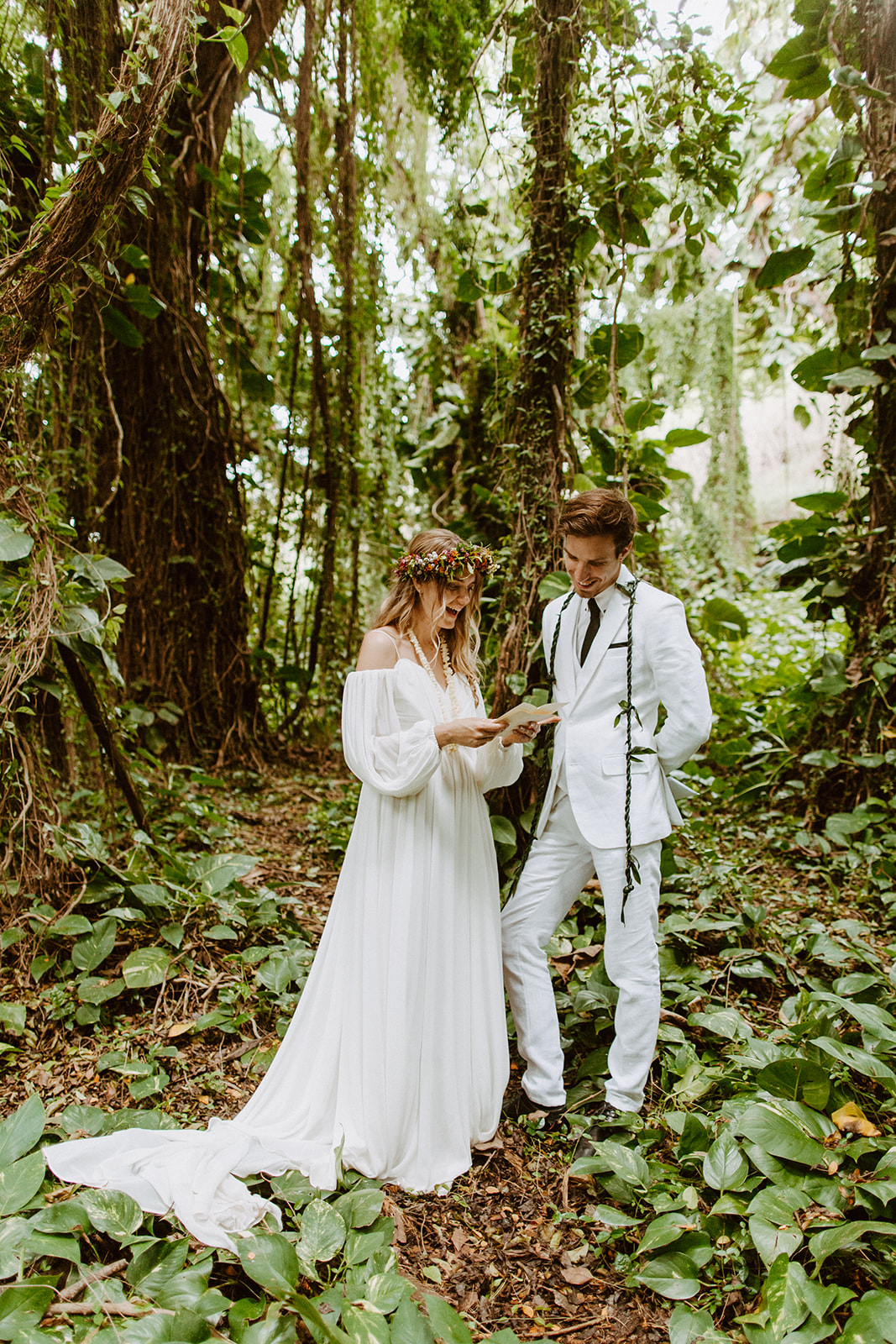 A couple who just got married opens letters from their Maui elopement in a hawaii forest with lush greenery and jungle 