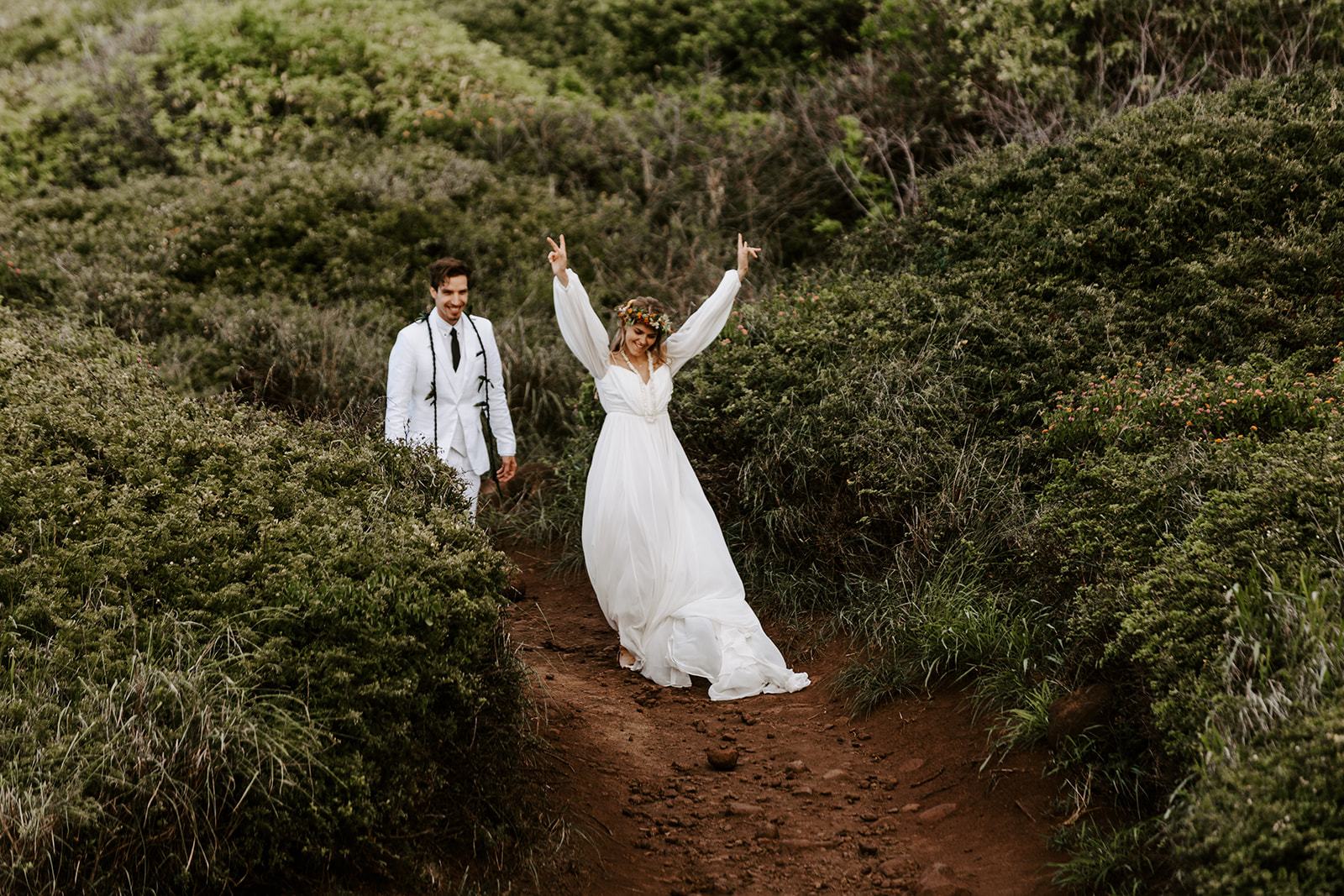A couple who had a Maui elopement cheers after their Hawaii cliffside wedding ceremony