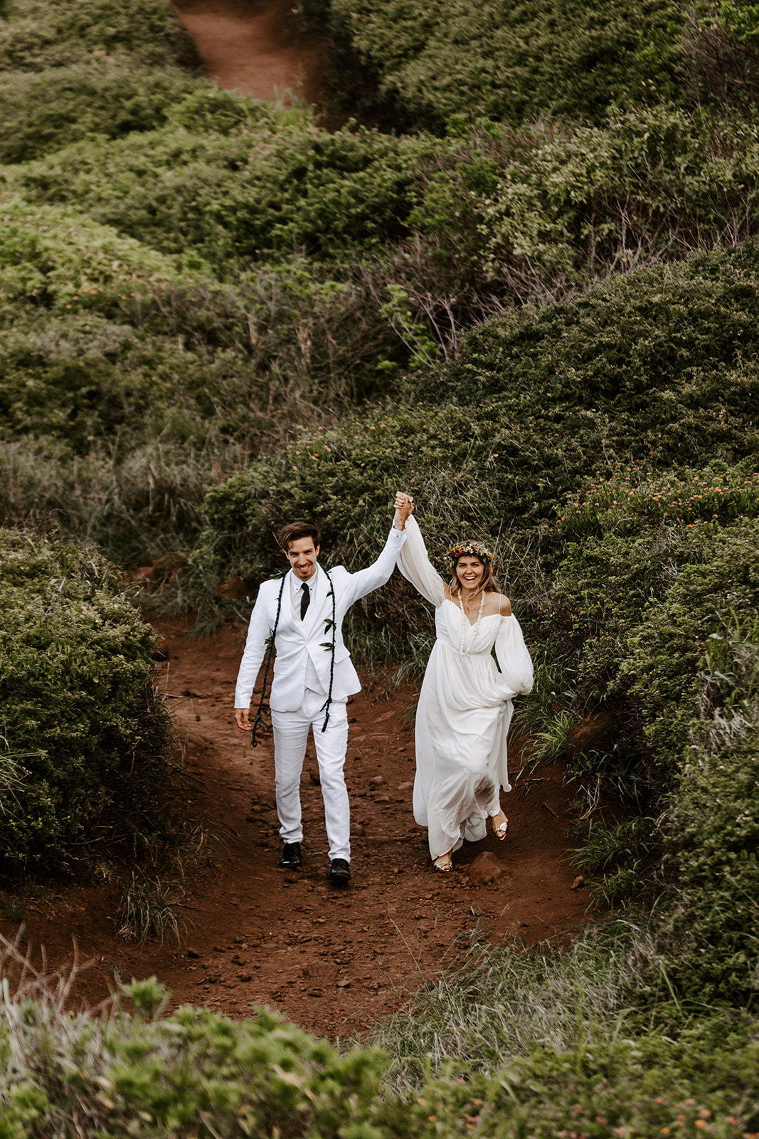A couple who had a Maui elopement cheers after their Hawaii cliffside wedding ceremony