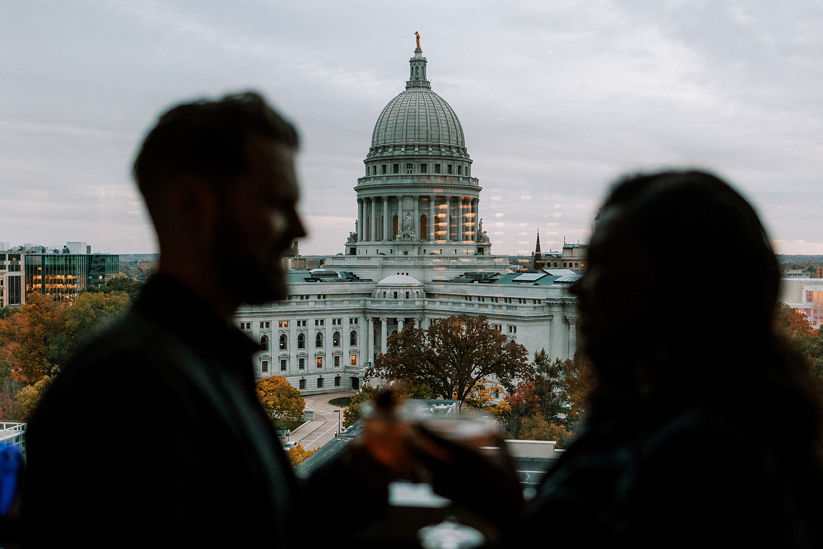couple enjoys a drink in front of the madison wisconsin capitol building during their late fall engagement session