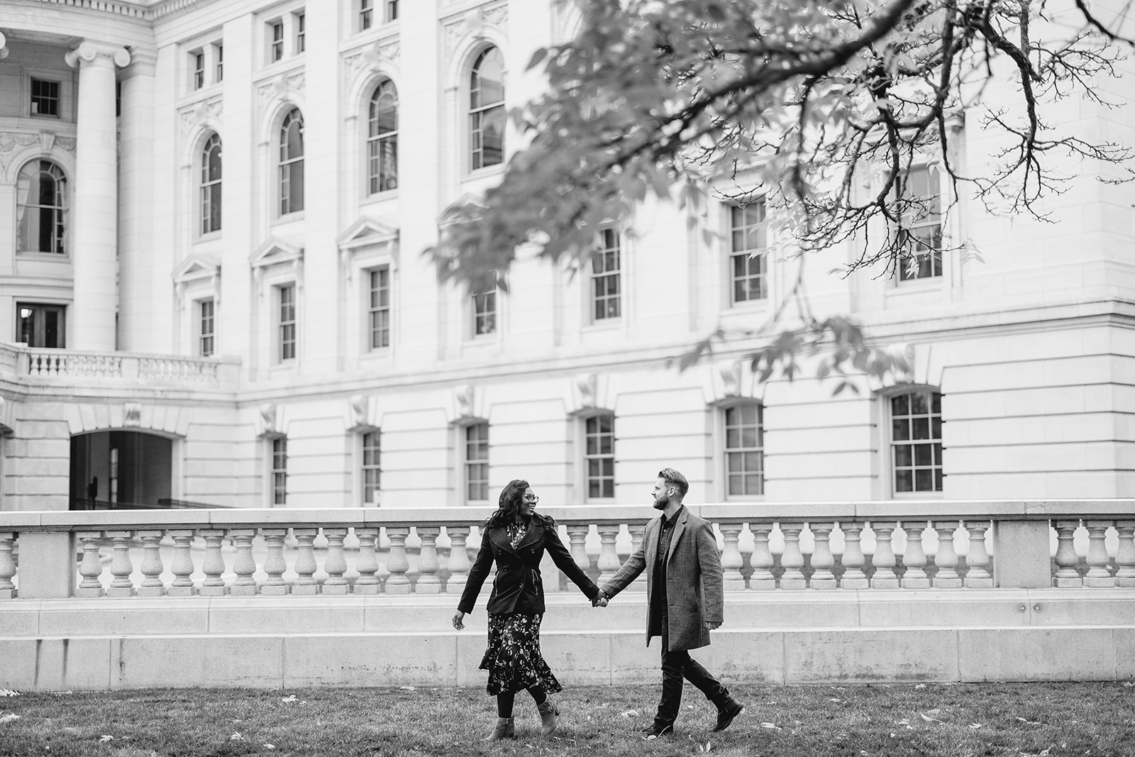 couple walks in front of the madison wisconsin capitol building during their late fall engagement session
