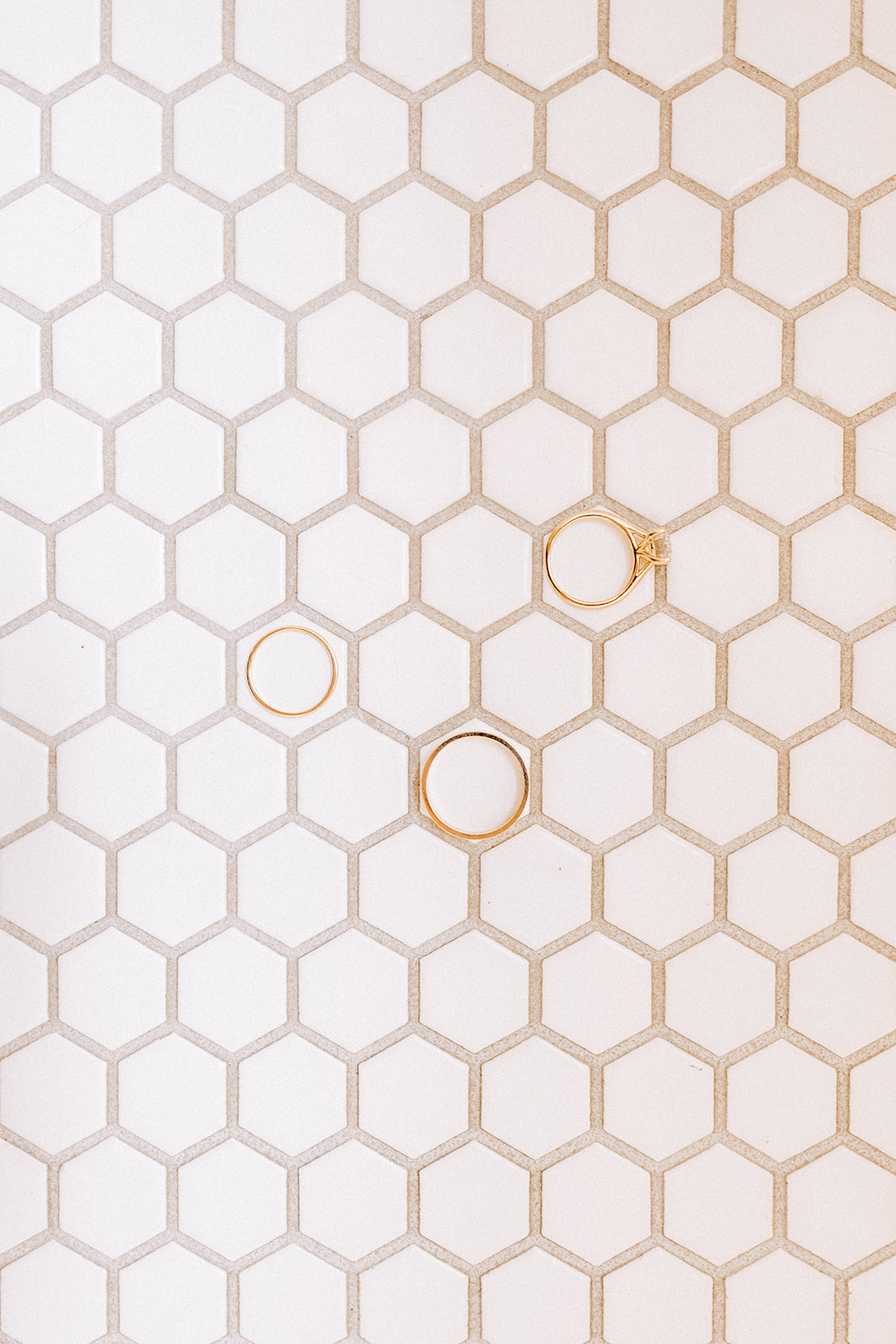 three gold rings are set on a tiled floor during a wedding day