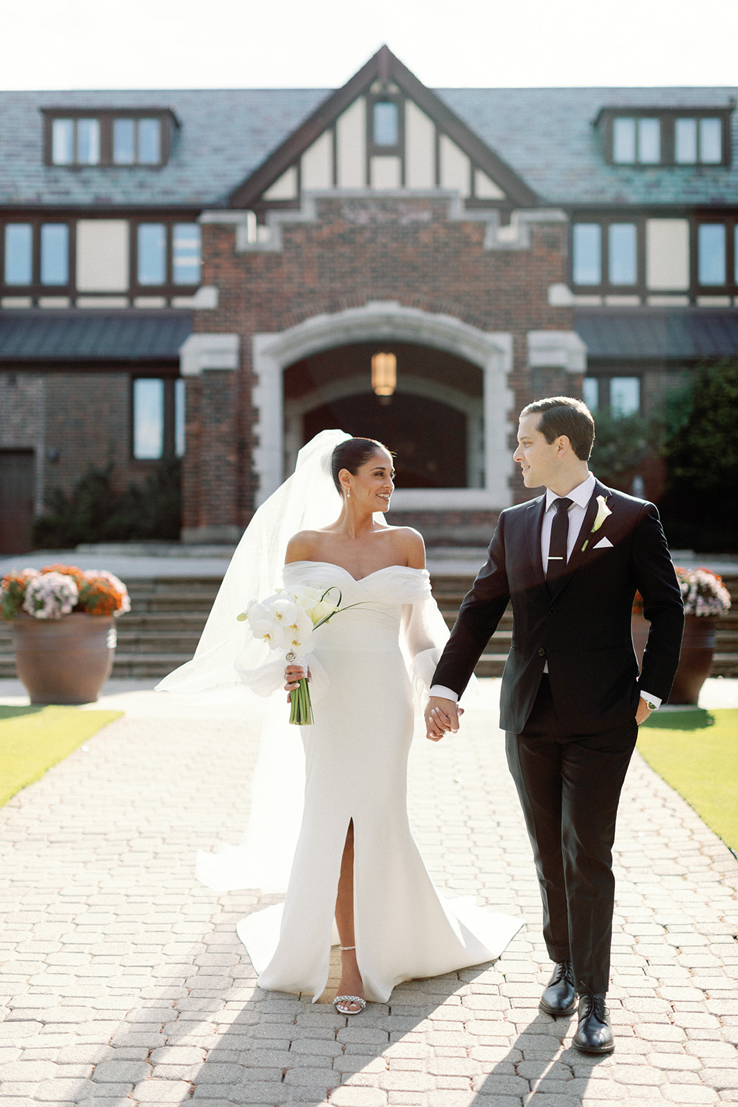 Bride and Groom holding hands and walking in front of Oak Hill Country Club