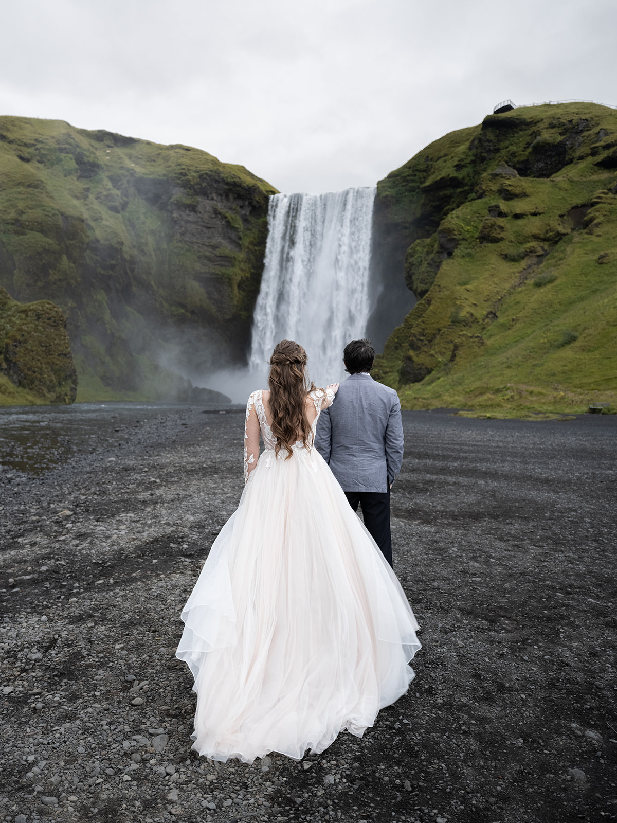 bride and groom having a first look at skogafoss in iceland during their elopement.