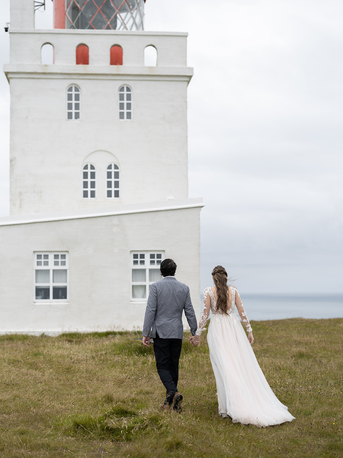 Bride and groom taking wedding portraits at dyrholaey lighthouse 