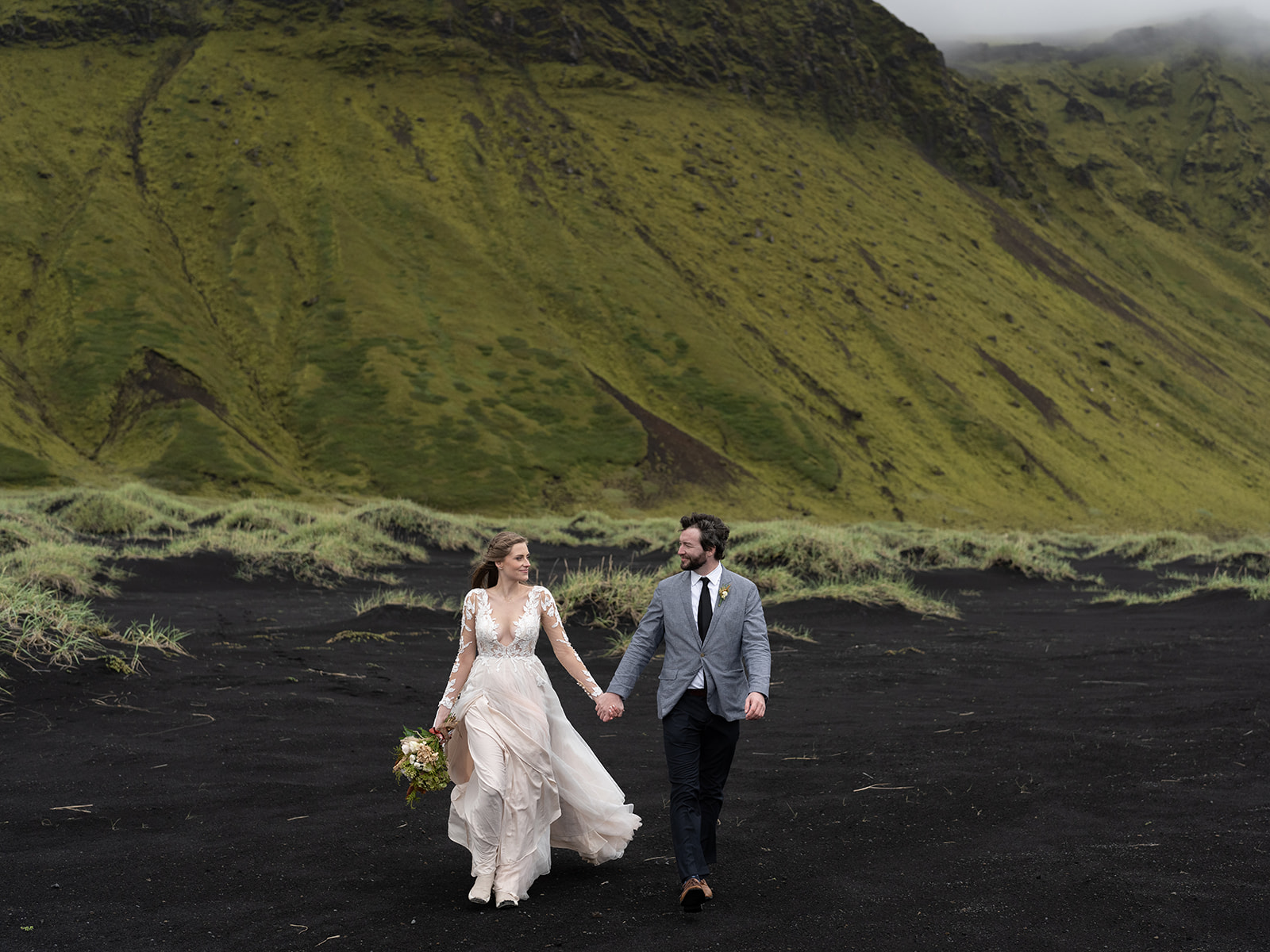 Bride and Groom walking on the black sands of iceland during their elopement 