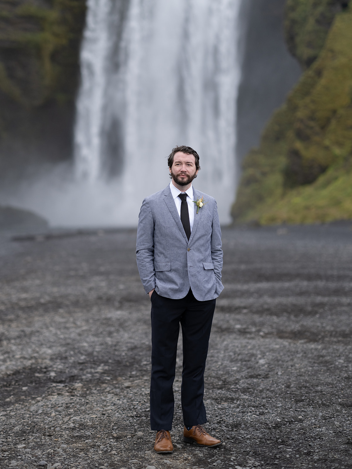 Groom standing in front of Skogafoss on his Elopement day