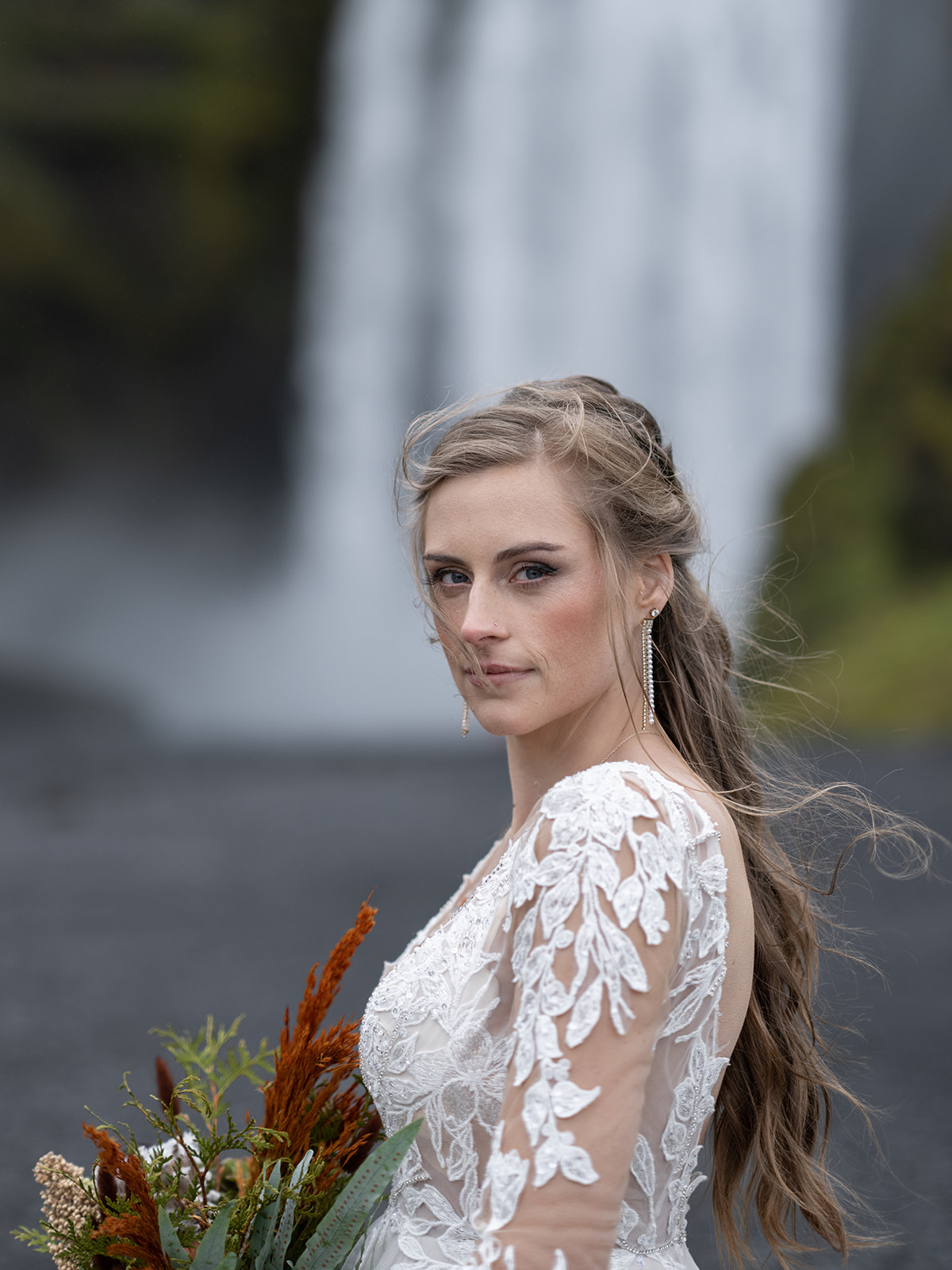 bride eloping in iceland stands in front of skogafoss