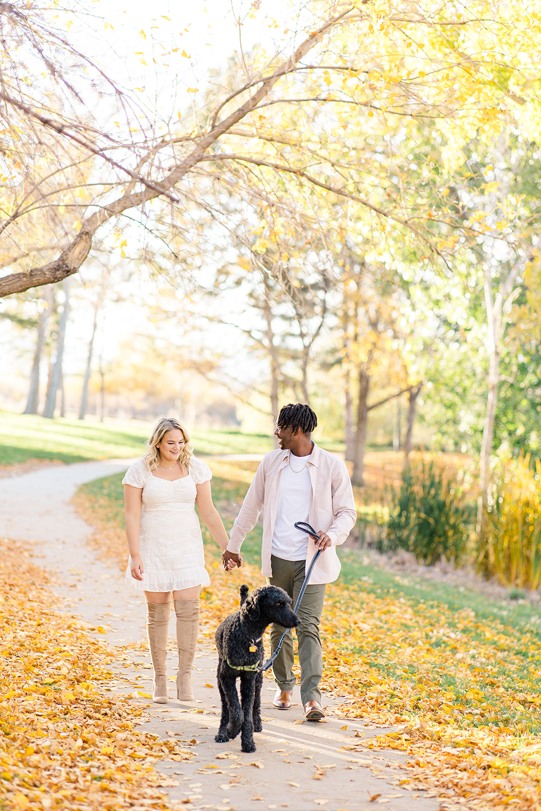 engagement portrait of couple walking with dog in fall colors at a park in Westminster, Colorado