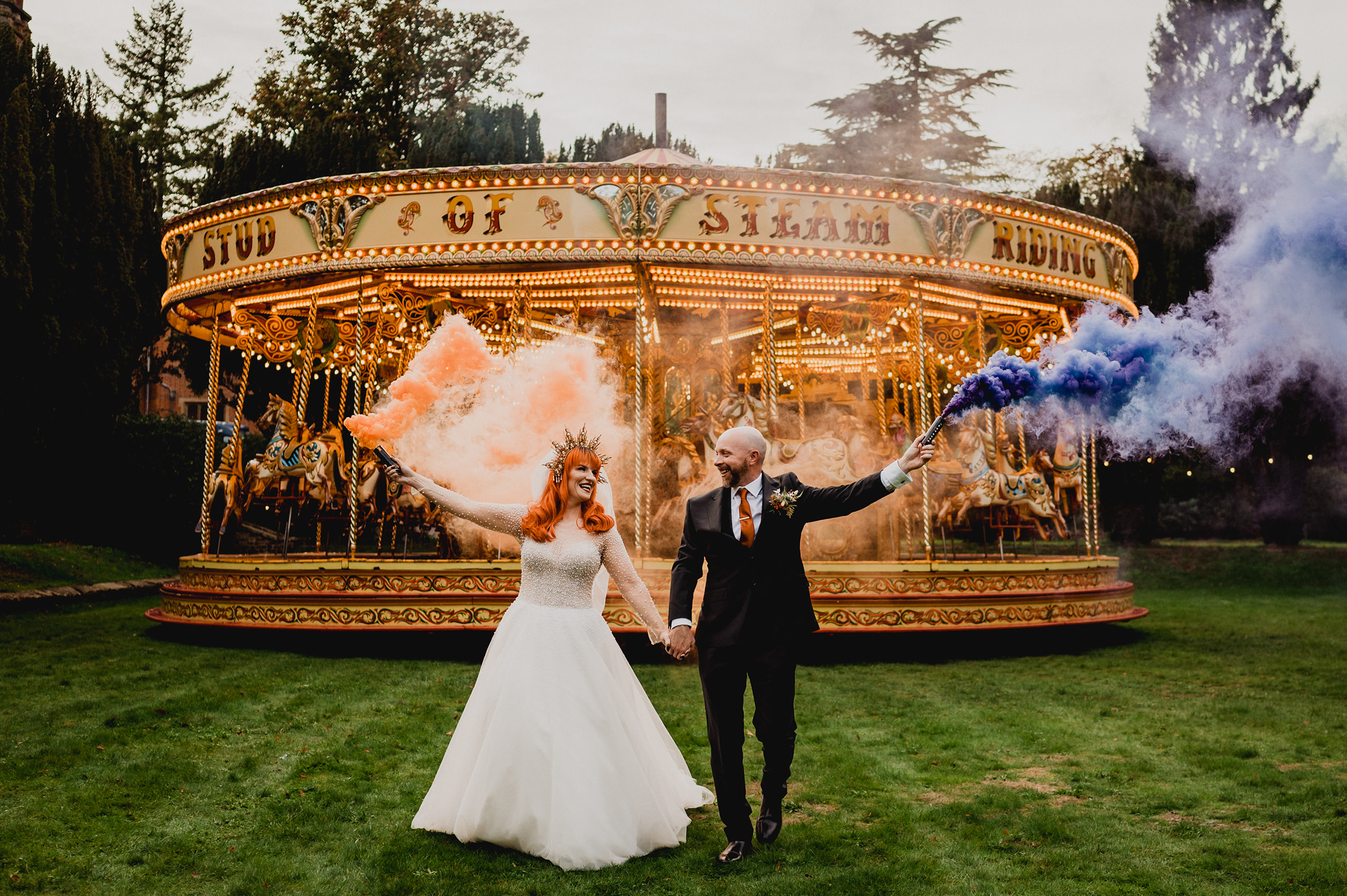 A bride and groom pose in front of a merry go round
