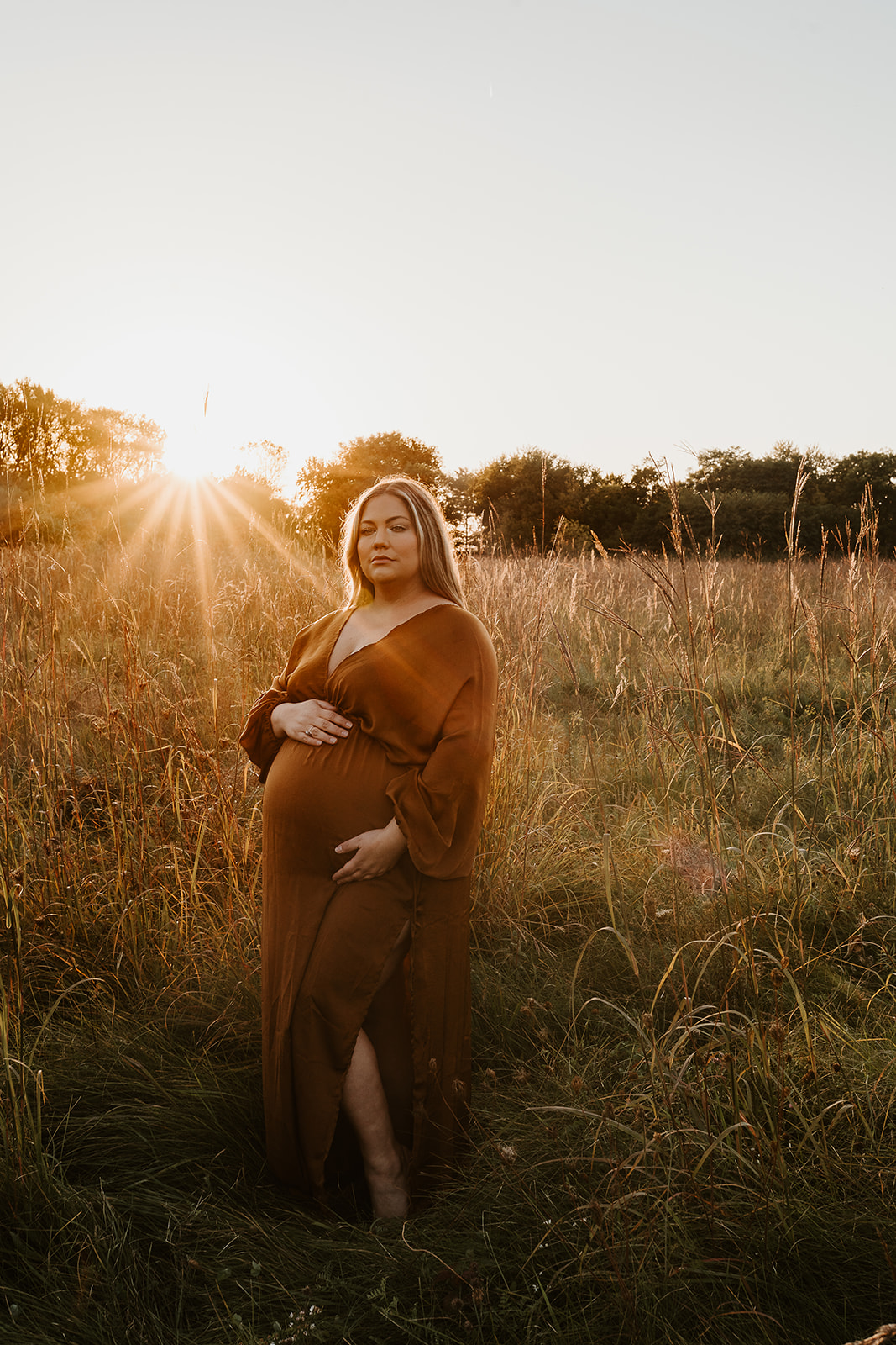 Pregnant mother wears a bronze gown in a vast field of tall grass in Fall