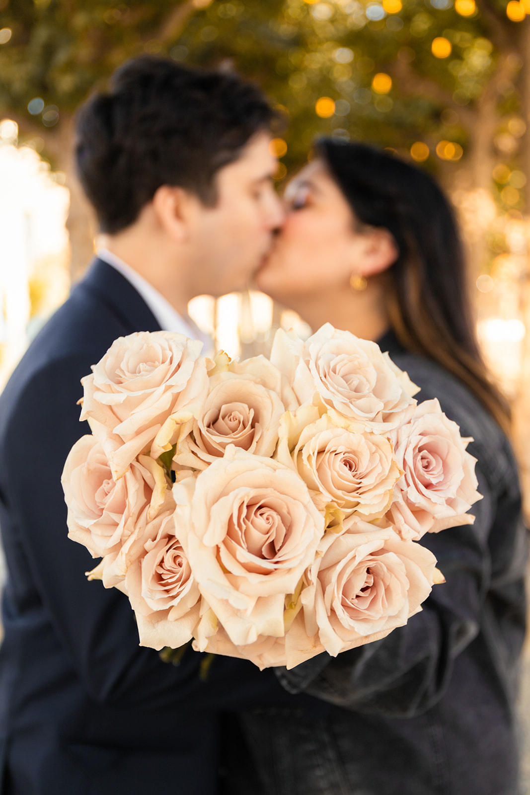 couple kiss bouquet in focus