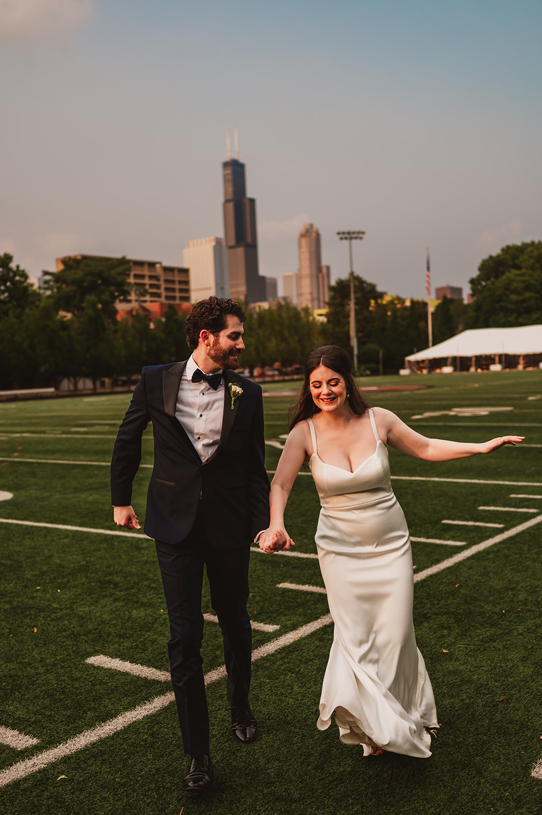 Bride and groom are running on the football field in Saint Ignatius College prep in Chicago photo