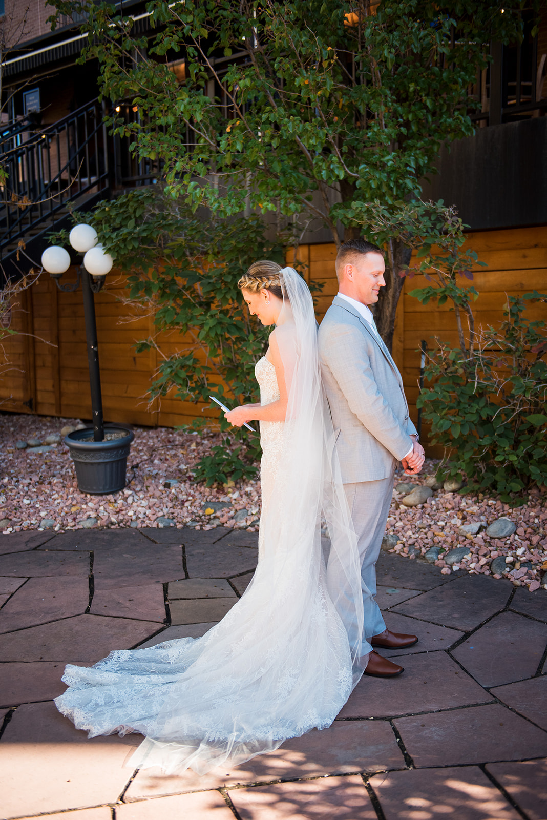 Bride and groom stand back to back while reading letters to each other.