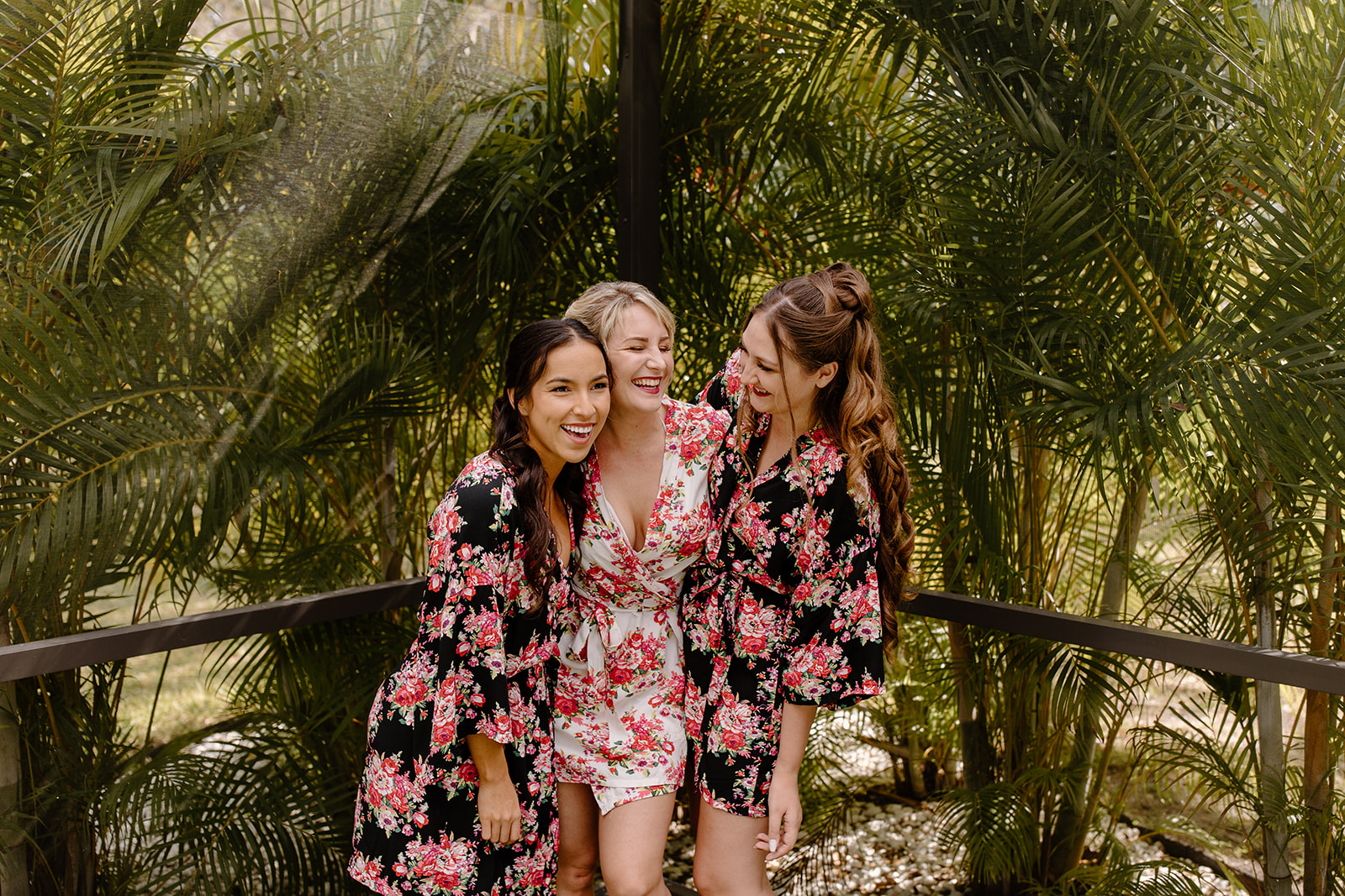 Bride and bridesmaids laughing in their matching floral robes