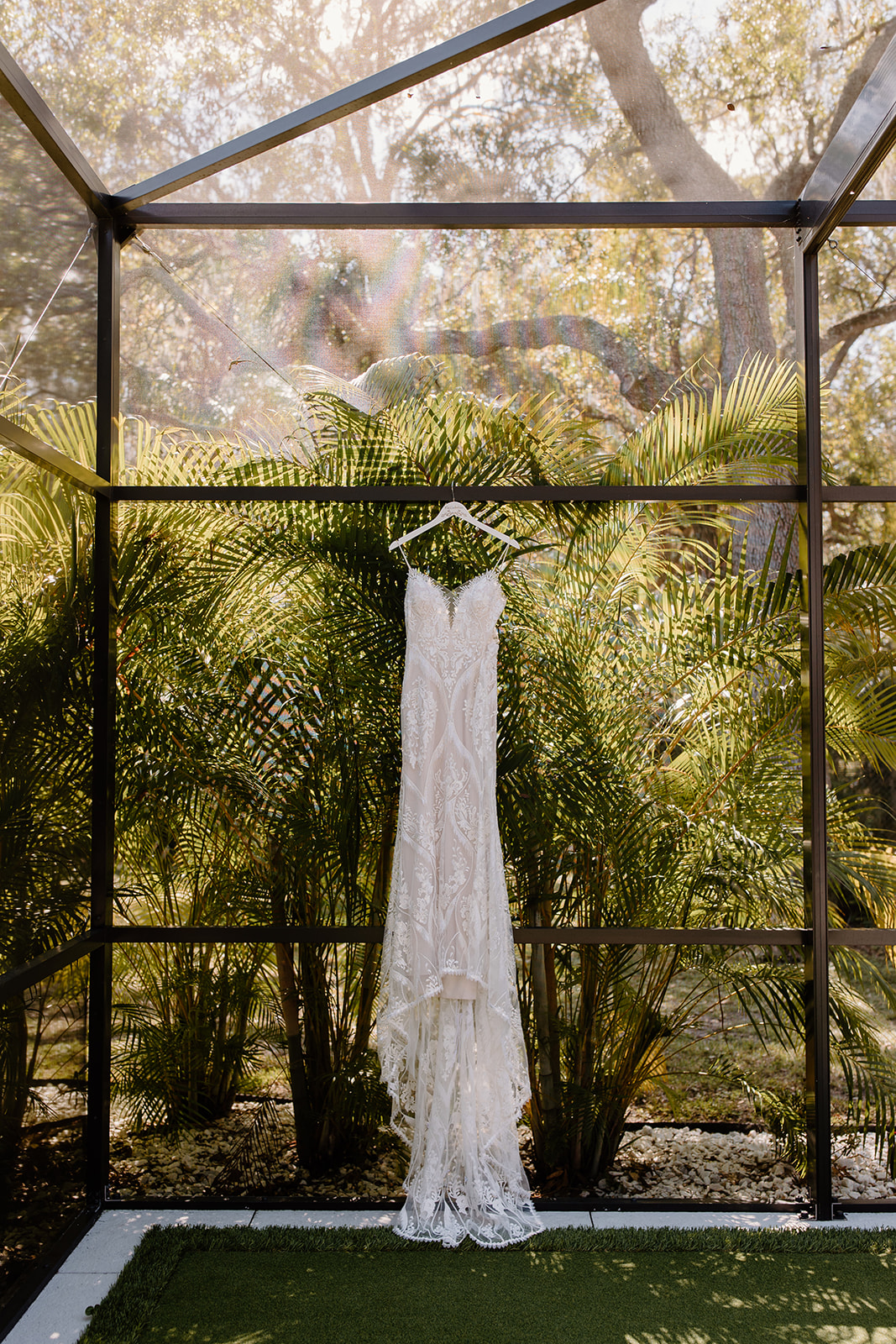 Wedding dress hanging up on a fence with ferns in the background 