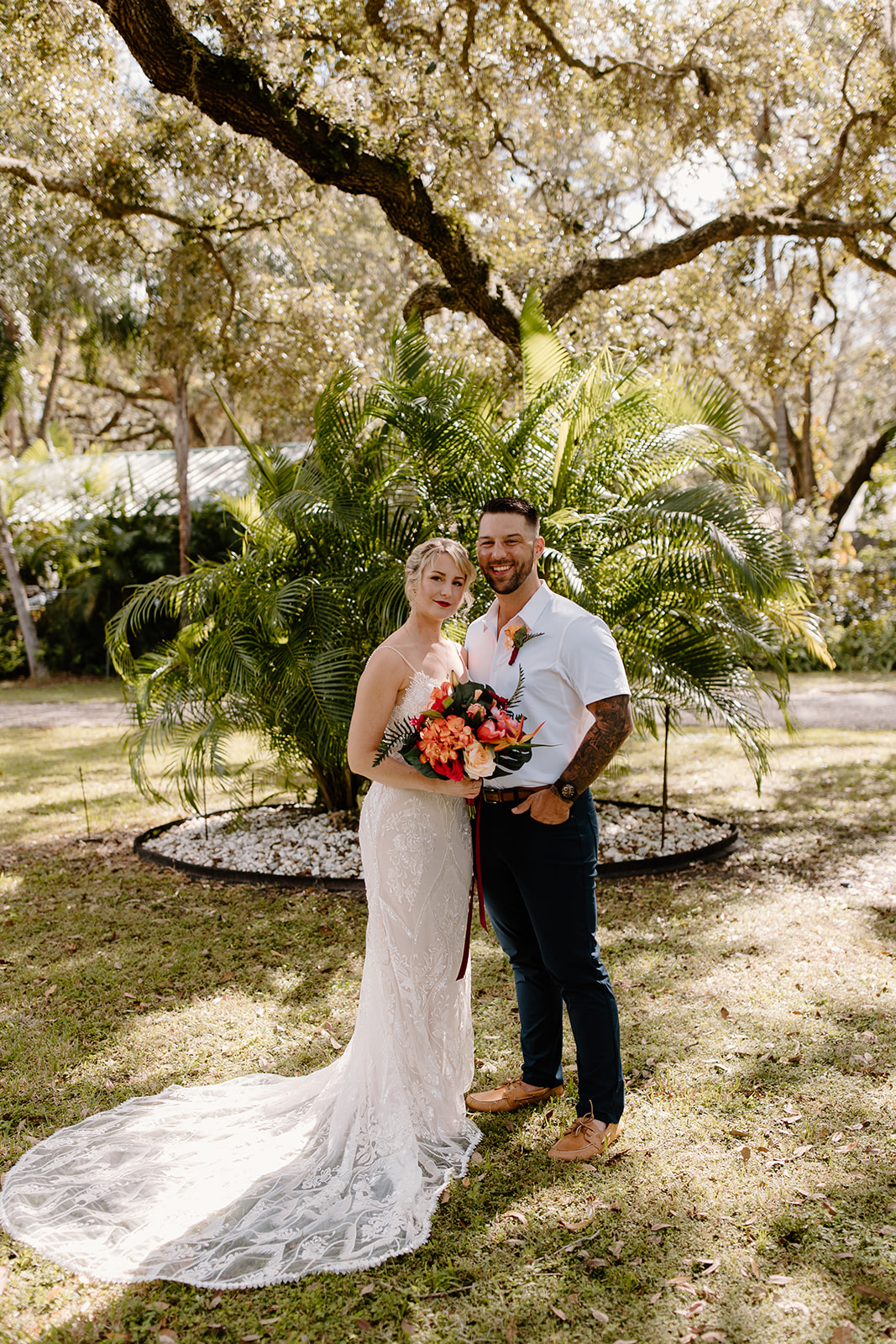 Bride and groom smile in front of a tree