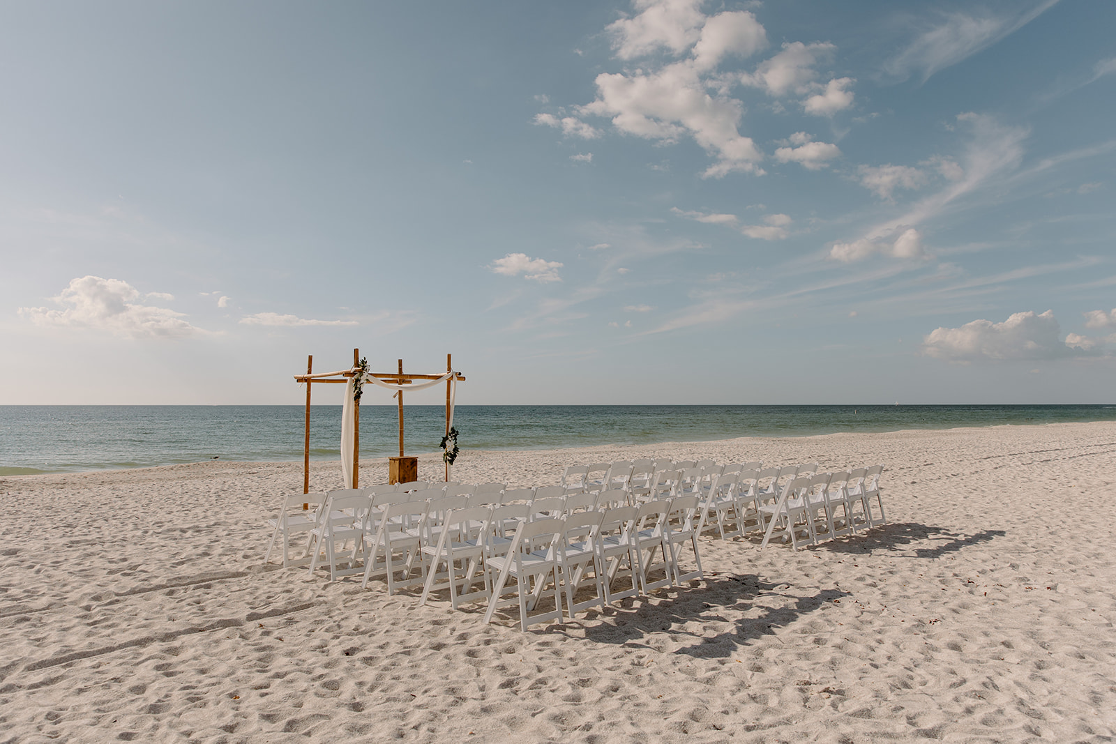 Ceremony site on the beach with the ocean and blue clouds in the back