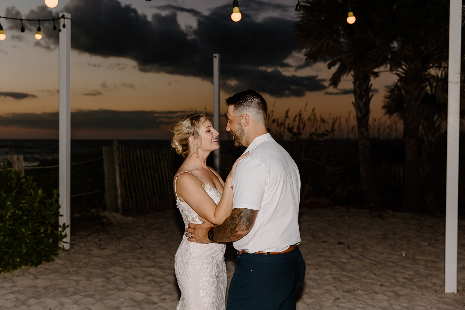 Bride and groom dance as the sun sets over the ocean