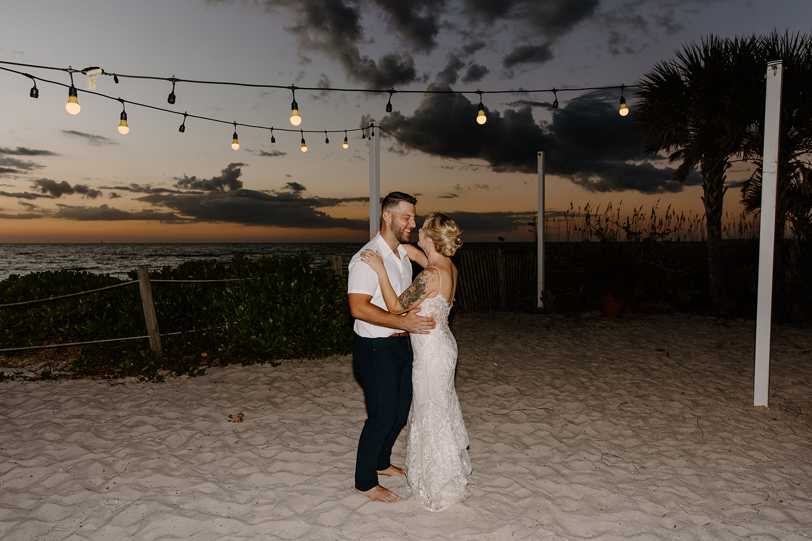Bride and groom dance as the sun sets over the ocean