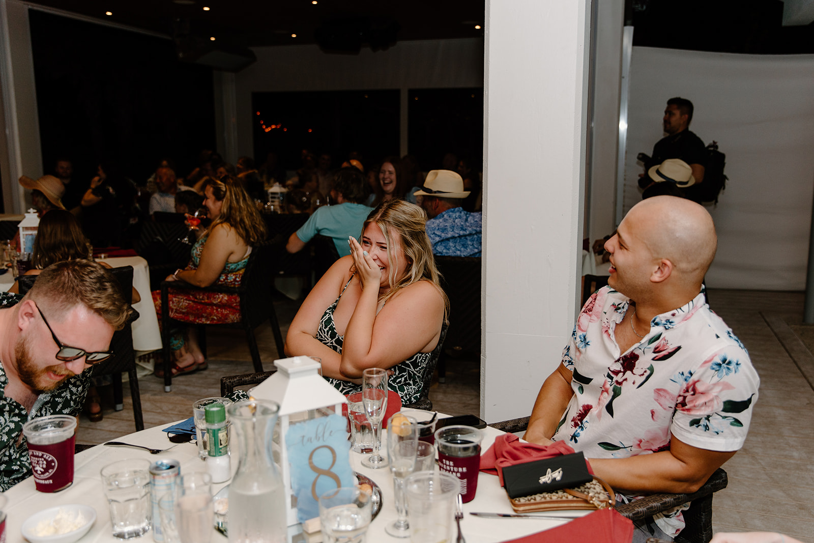 Guests laugh at their dinner tables
