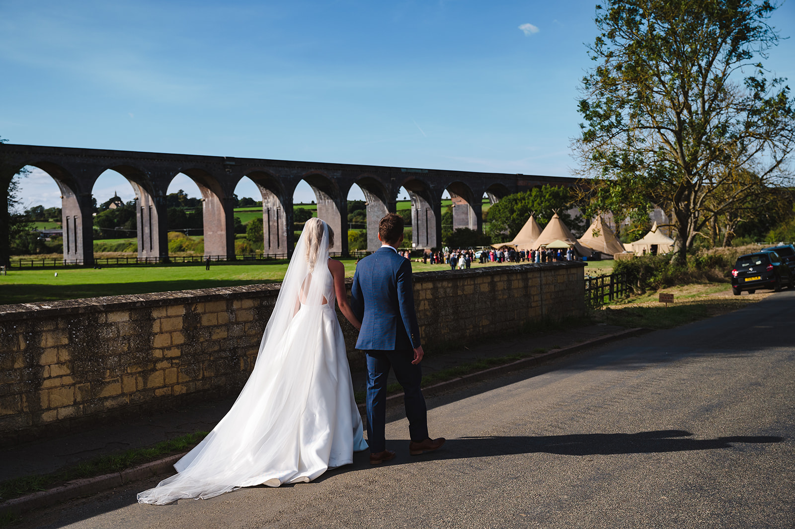 bride and groom walking towards harringworth viaduct