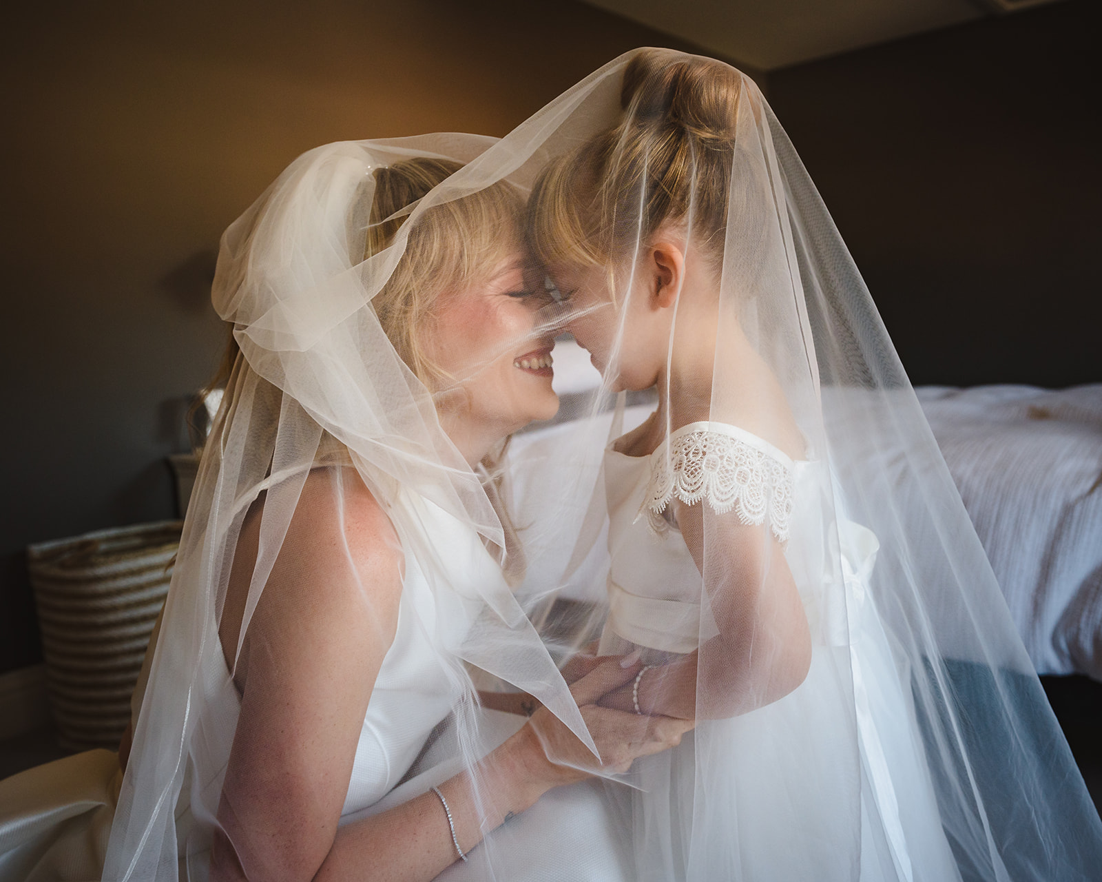 a bride with her little girl under her veil on the wedding morning