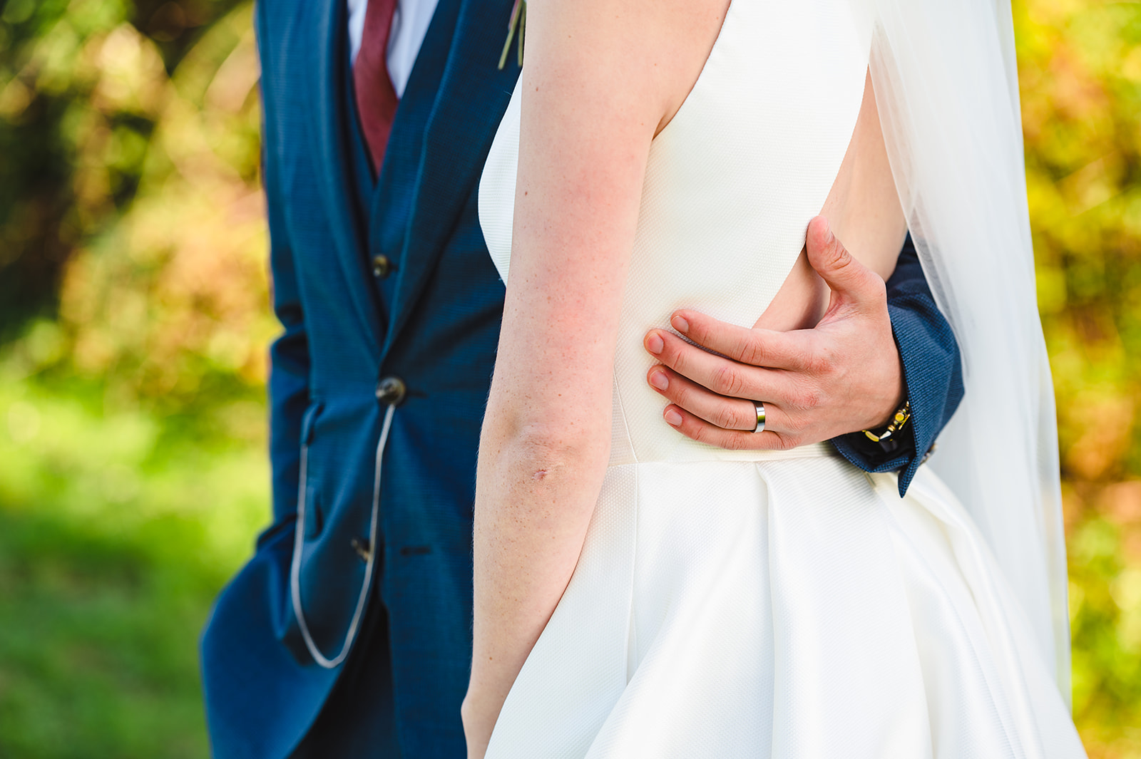 Close up of groom holding his bride around her waist
