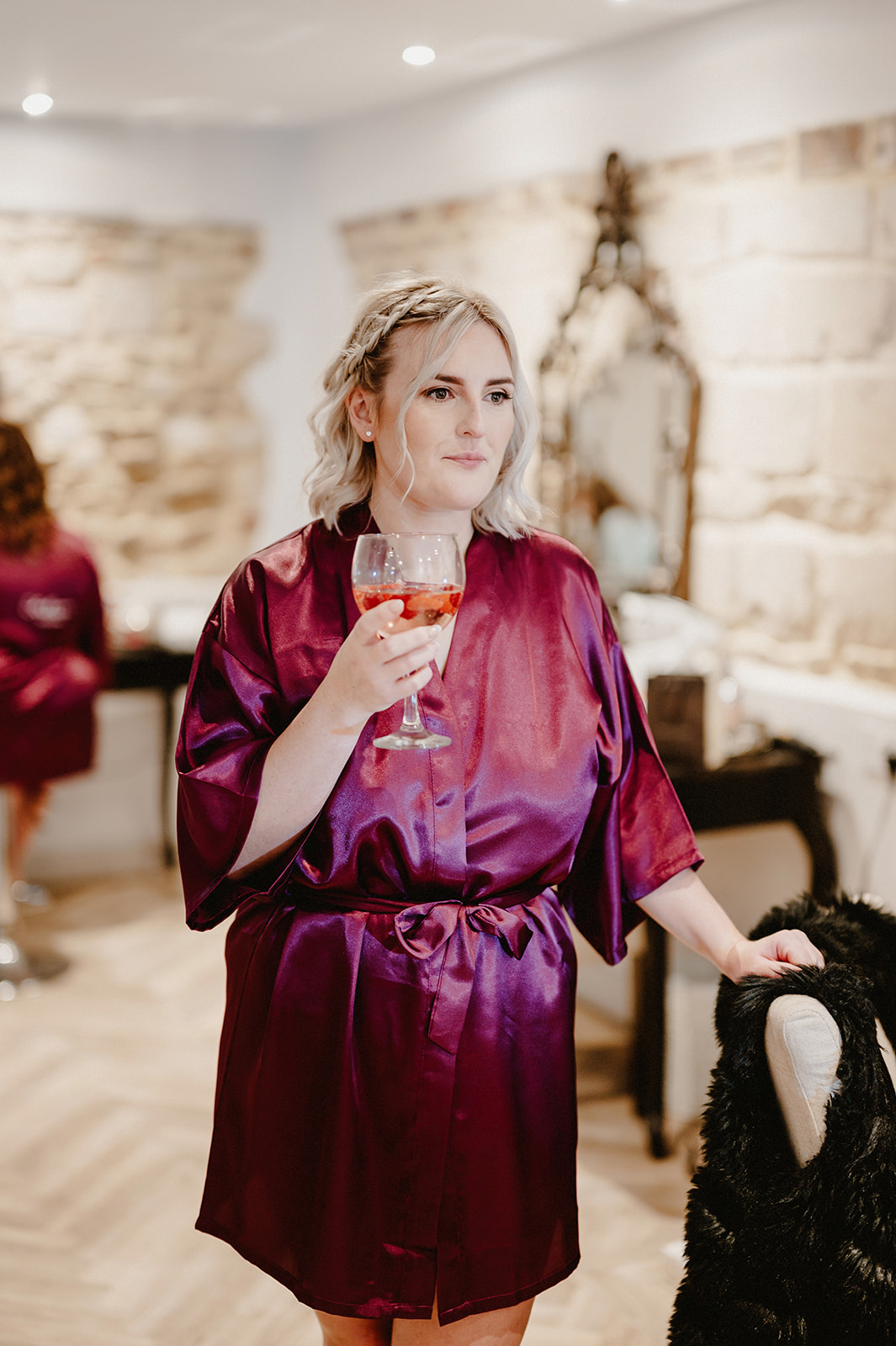 wedding photograph of a bridesmaid in dressing gown drinking a glass of bubbly at pentney abbey