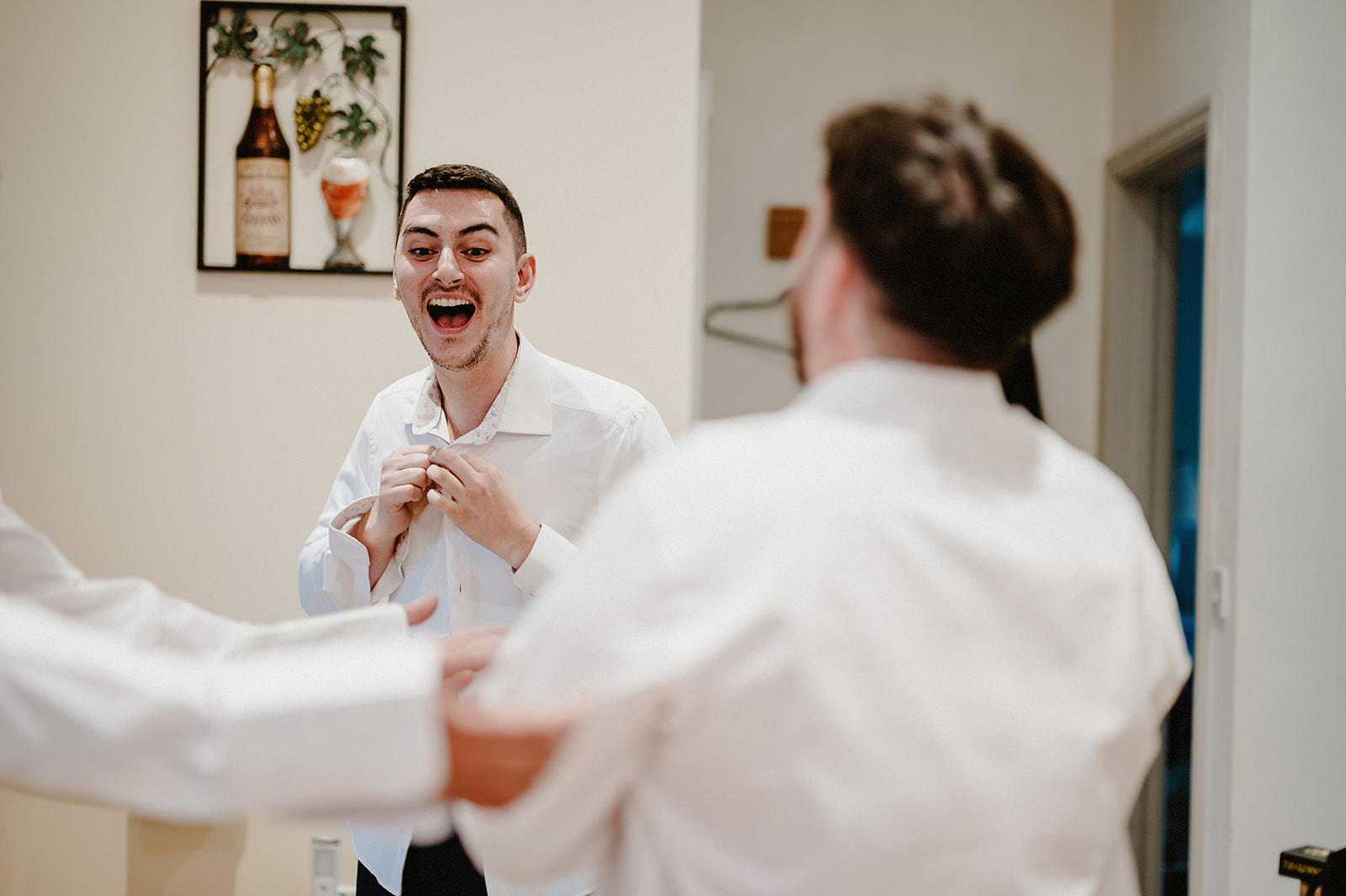 Wedding photography photo of the groom laughing whilst getting dressed