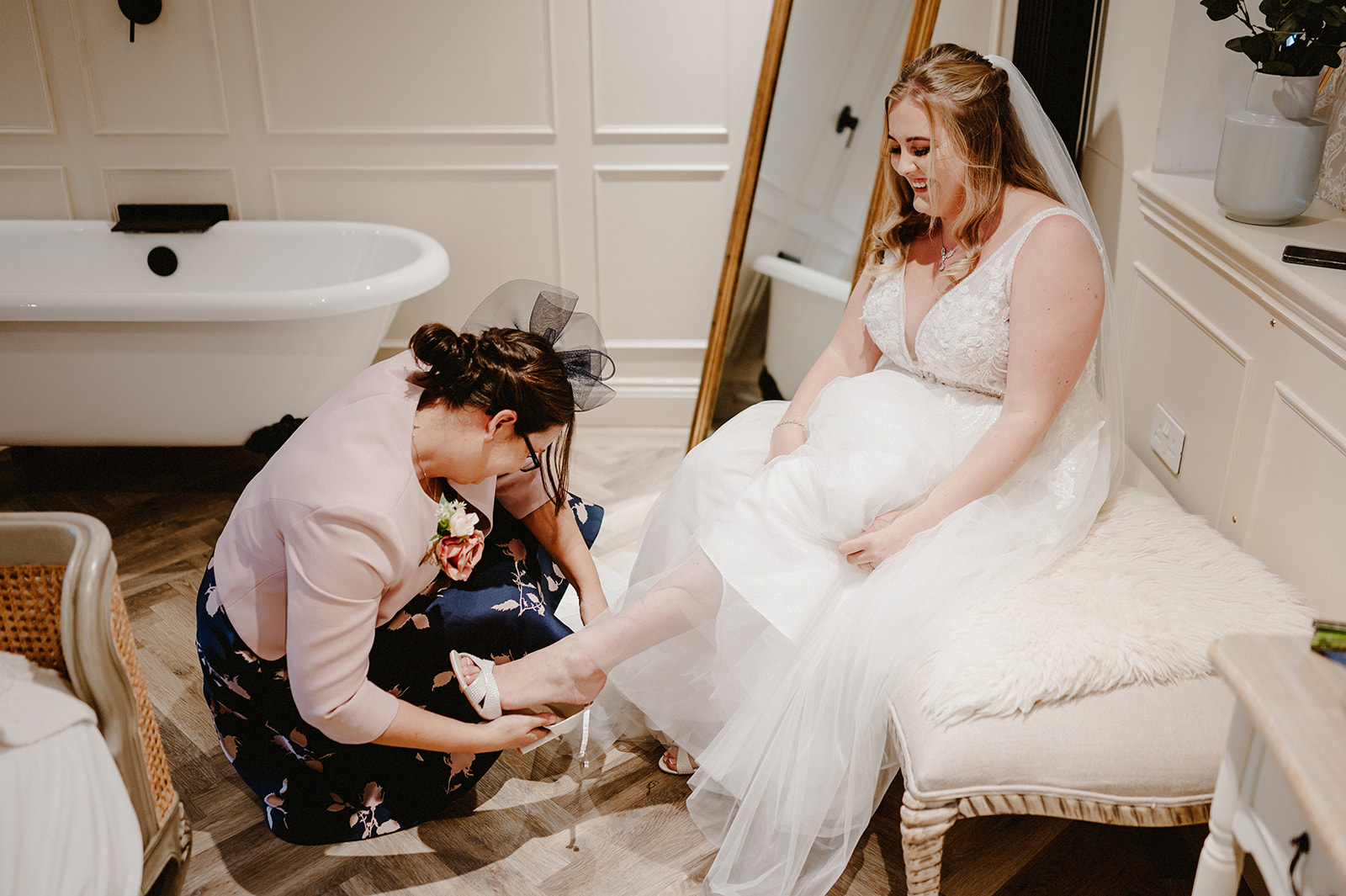 bride having her shoes placed on her feet by her mother on her wedding day