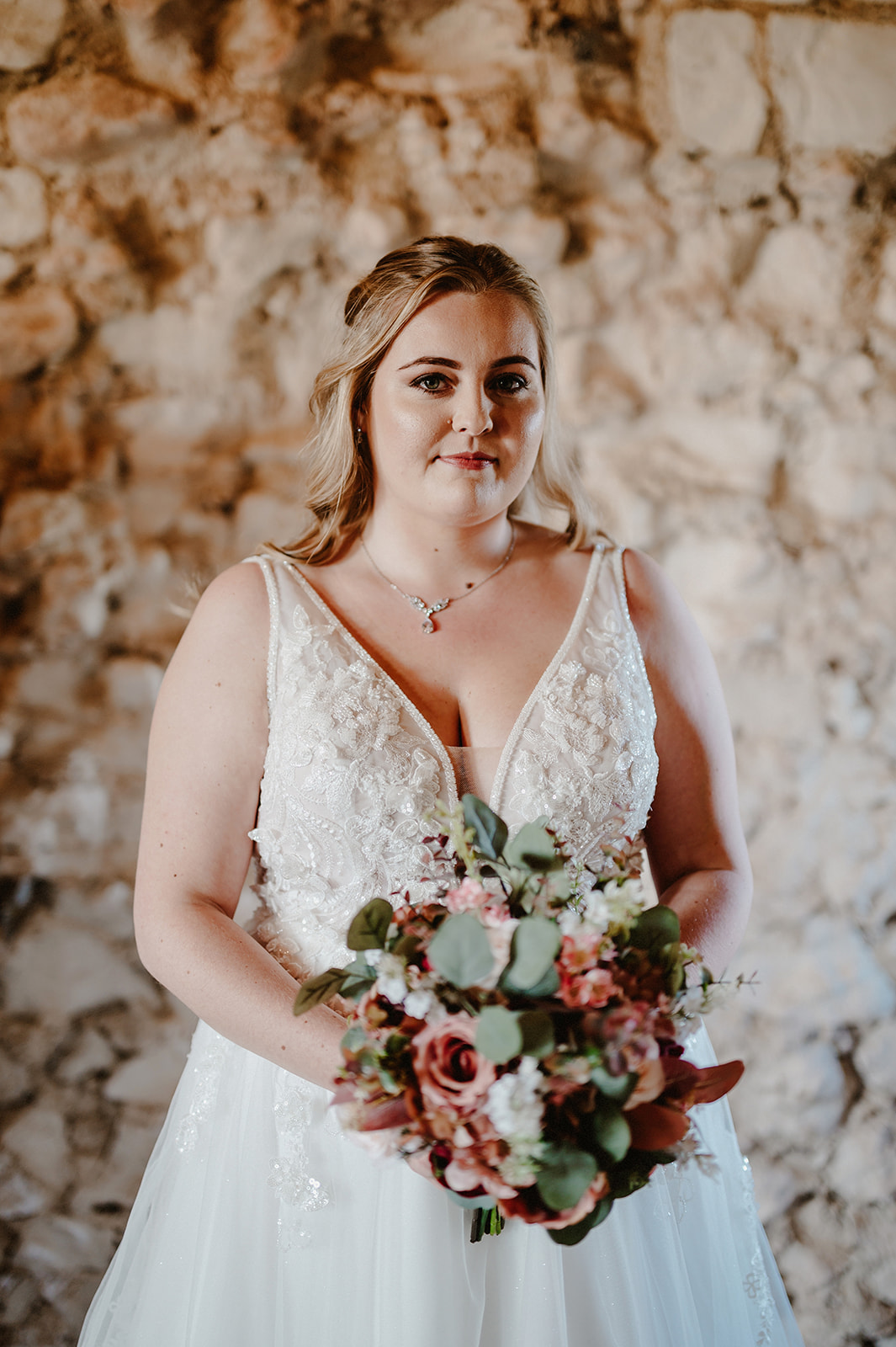 beautiful bride in front of a bare brick wall at pentney abbey smiling minutes before the wedding ceremony by james pearce wedding photographer