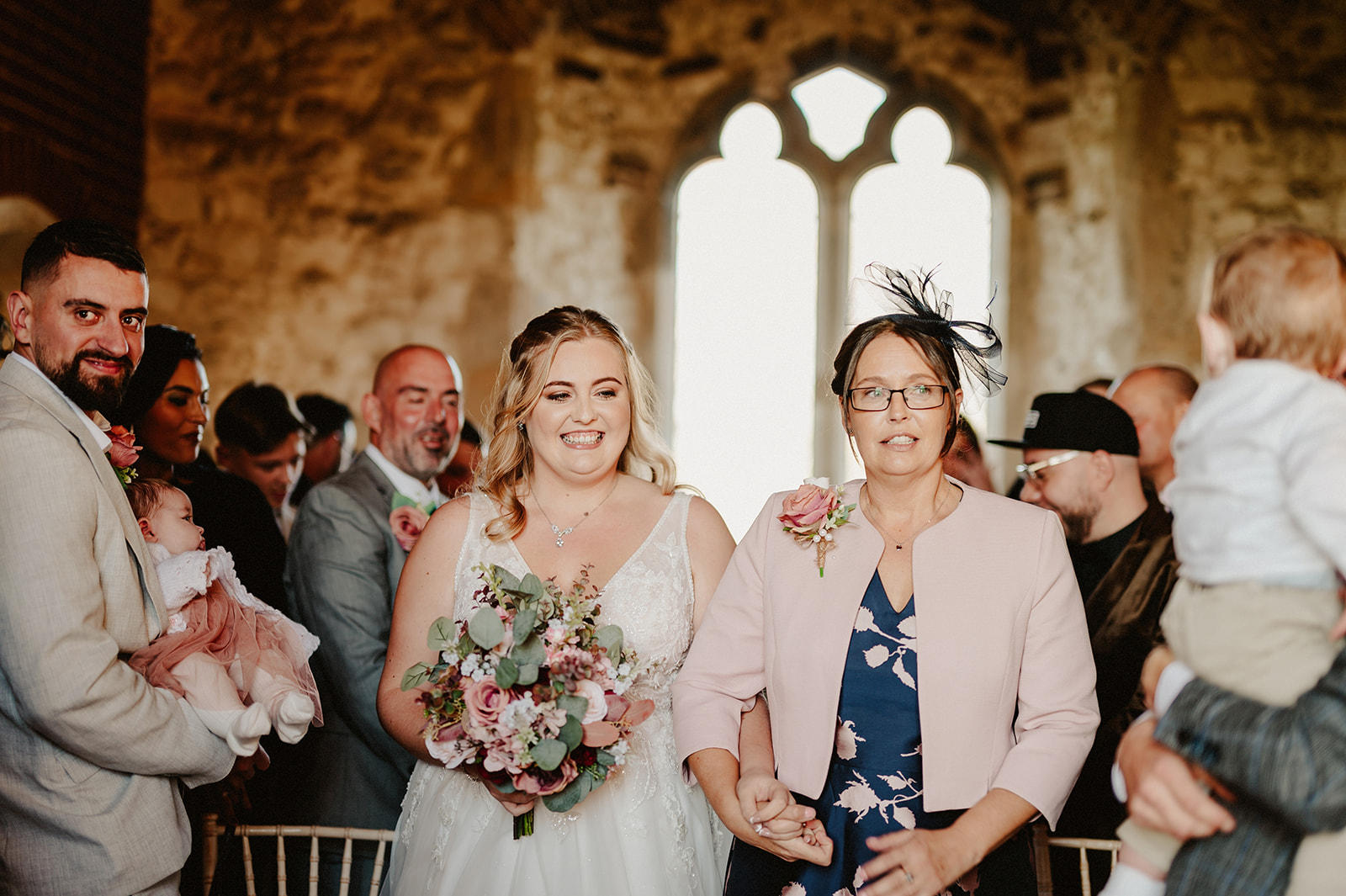 bride is walked down the aisle by her mother on her wedding day at pentney abbey wedding venue norfolk