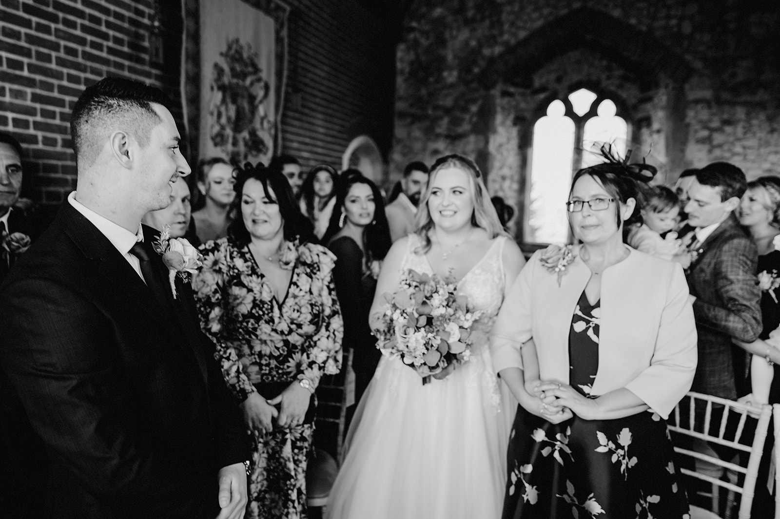bride is walked down the aisle by her mother black and white wedding photo