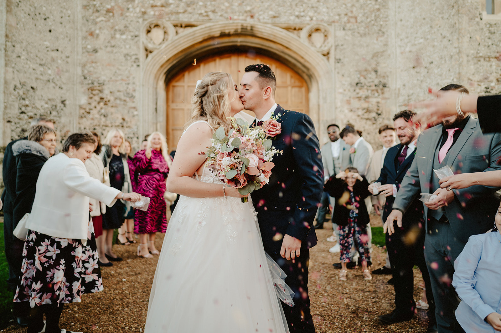 a kiss during the fun confetti throw minutes after the wedding ceremony at pentney abbey