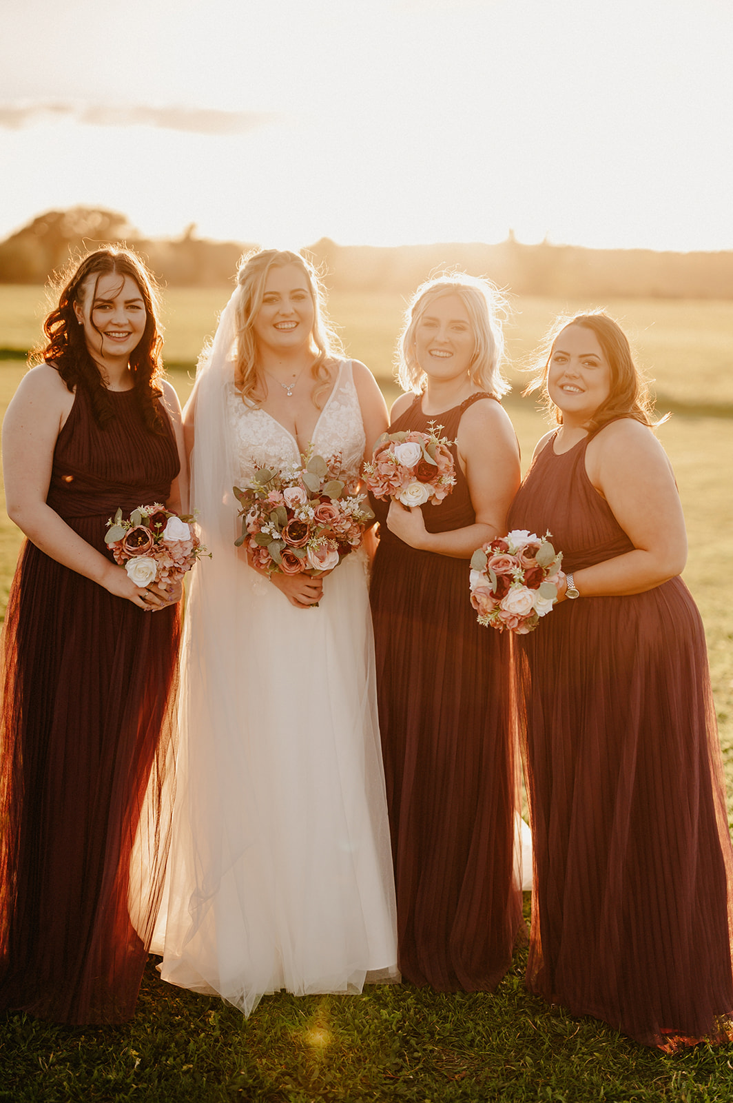 bridesmaids wearing red pose for a golden hour portrait with bride at pentney abbey