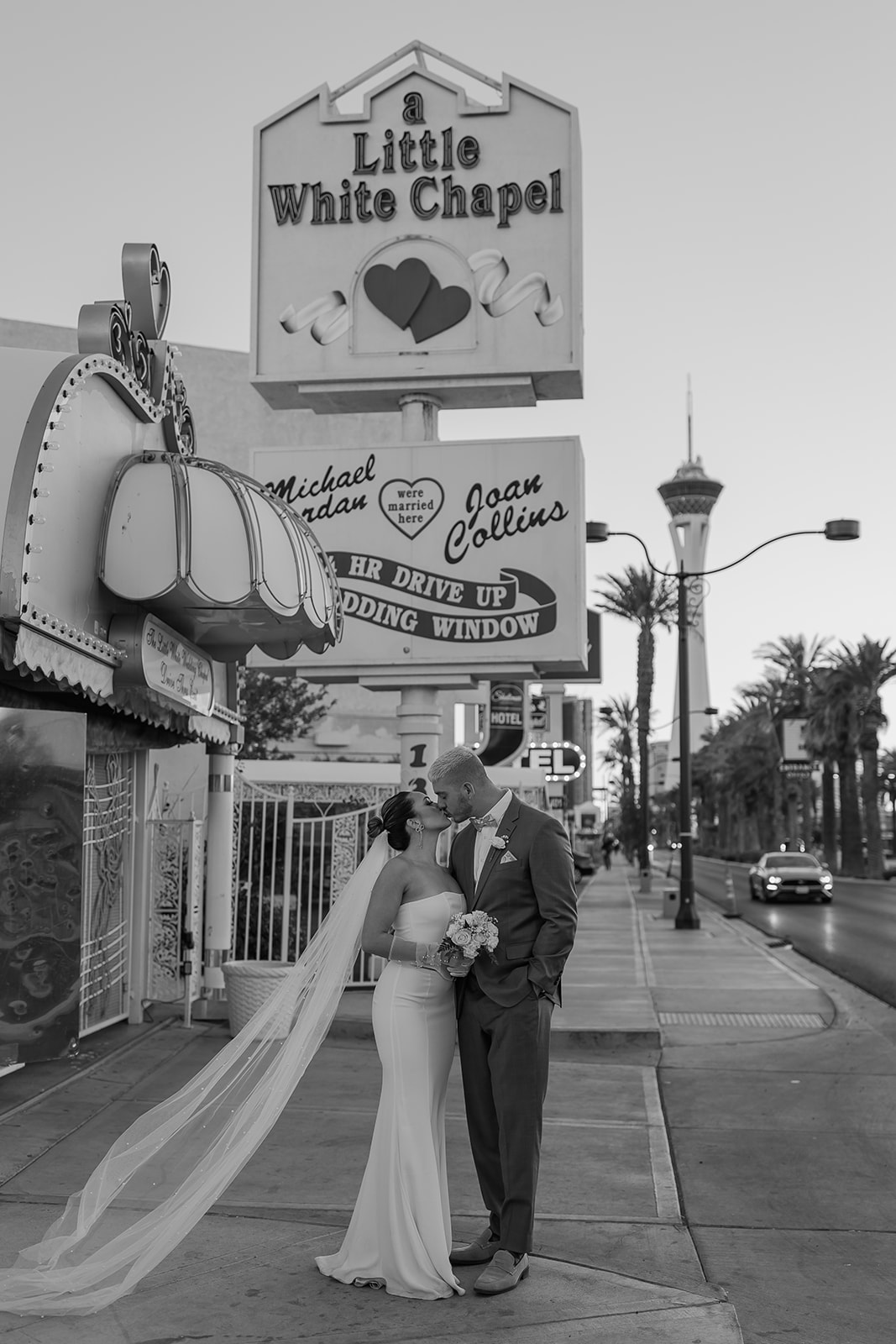 Bride and groom stand in front of the little white chapel sign