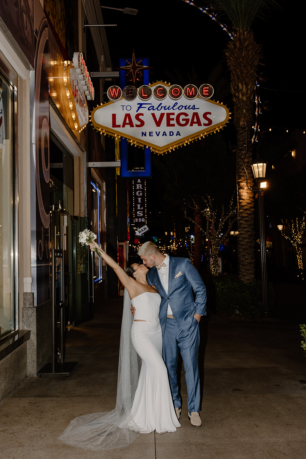 Bride and groom kiss under a welcome to Las Vegas sign