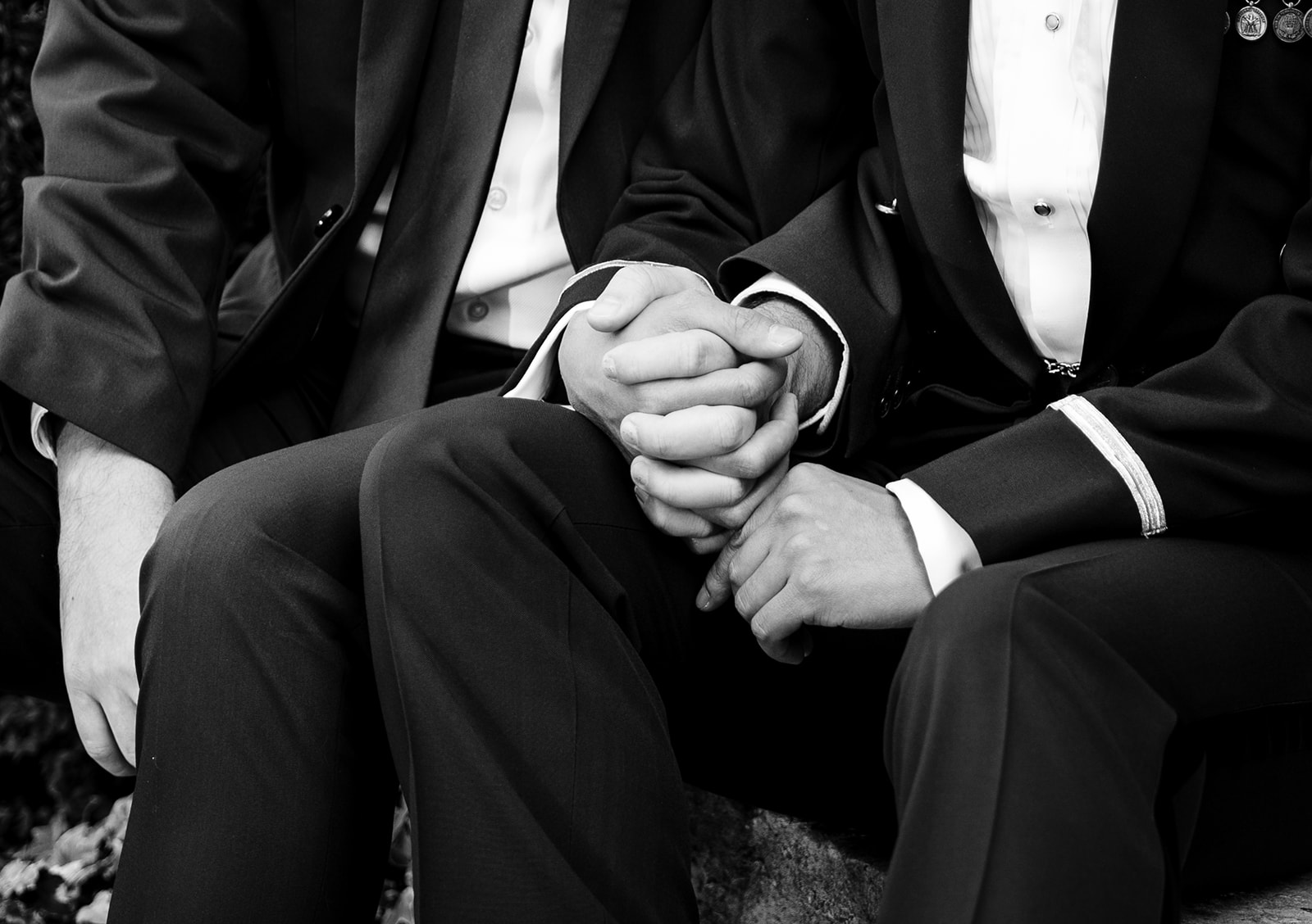 A black and white image of two grooms holding hands