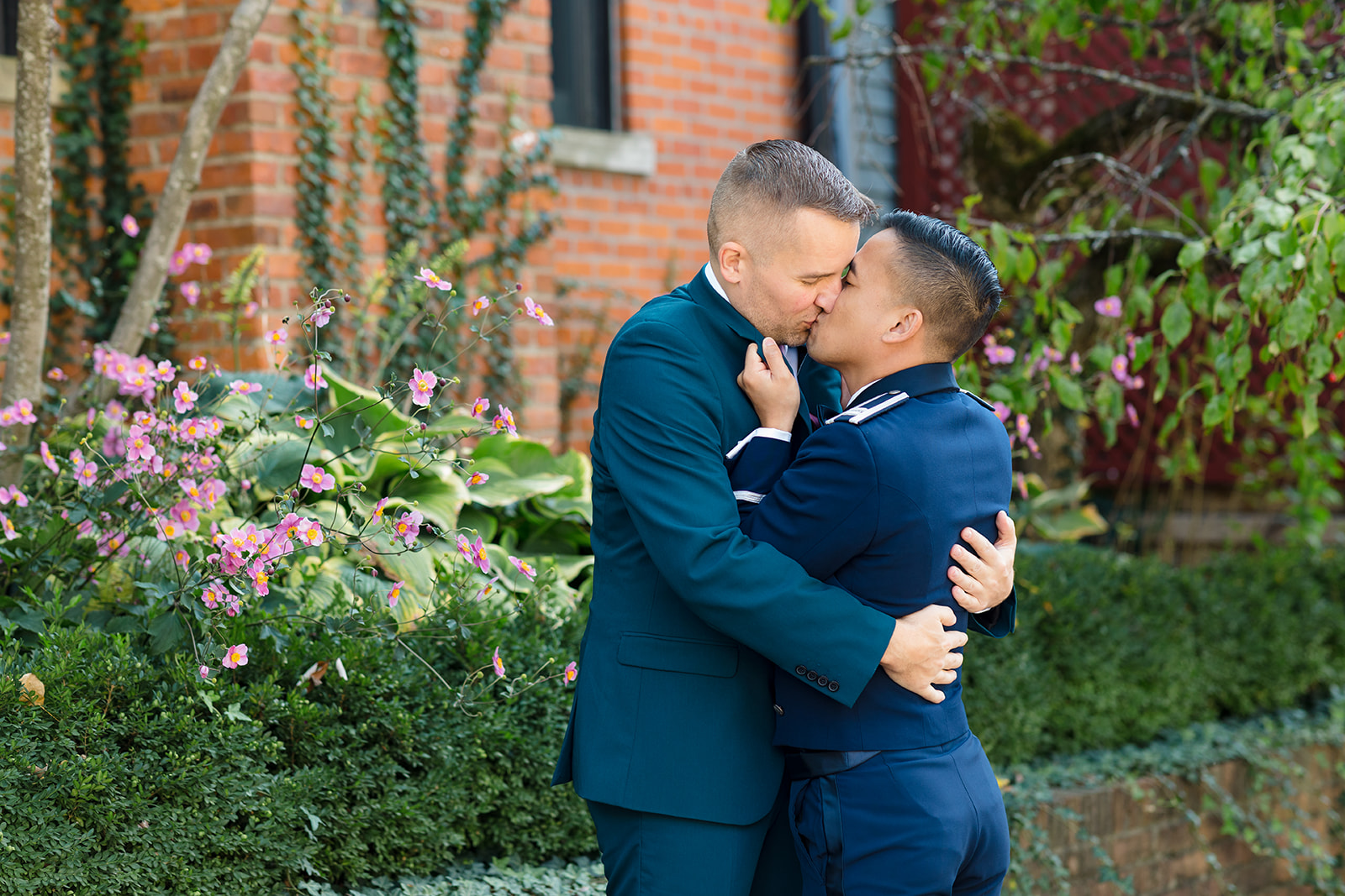 Two grooms passionately embrace and kiss just before their wedding