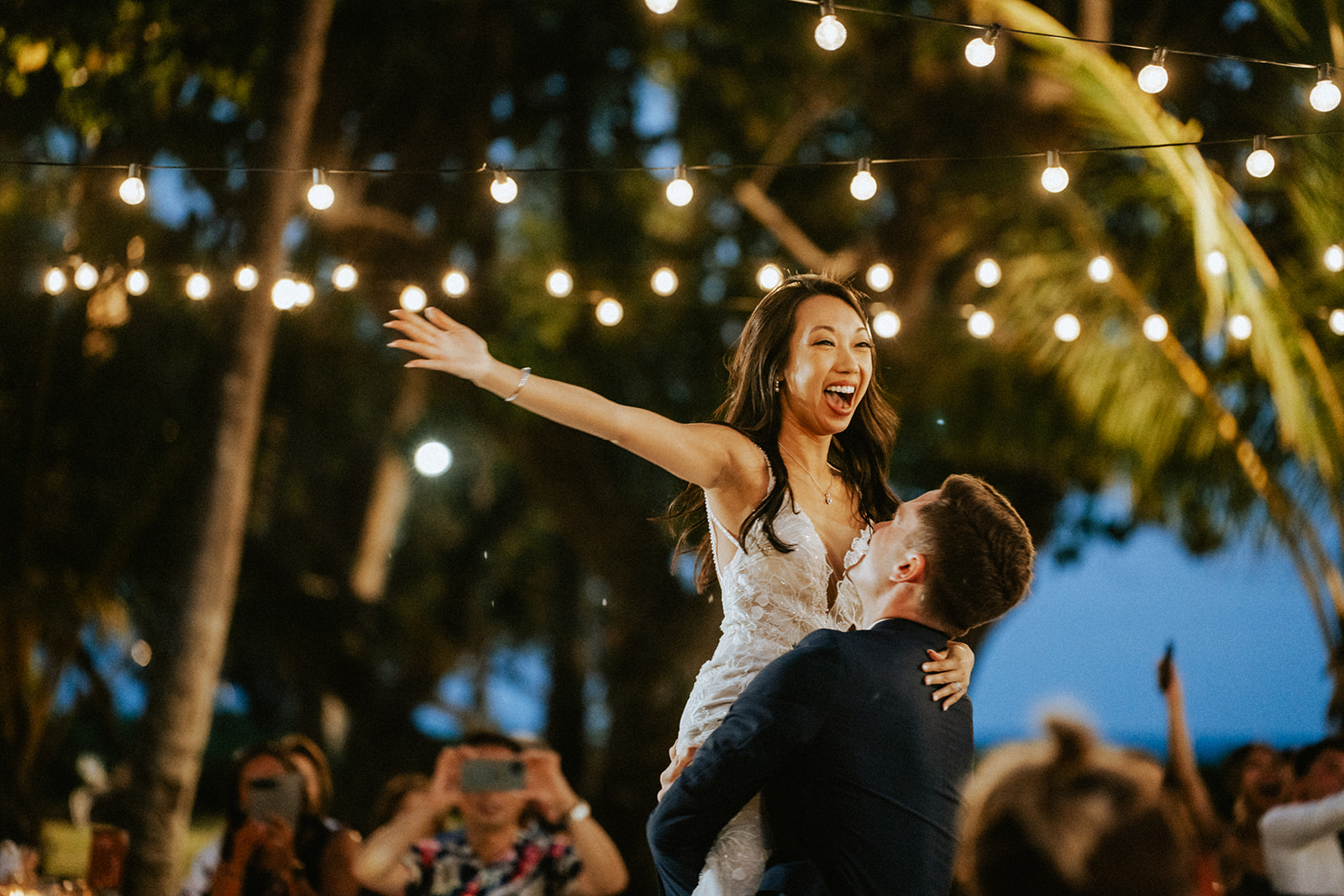 Groom and Bride have a first dance at Lanikuhonua during dusk under cafe lights