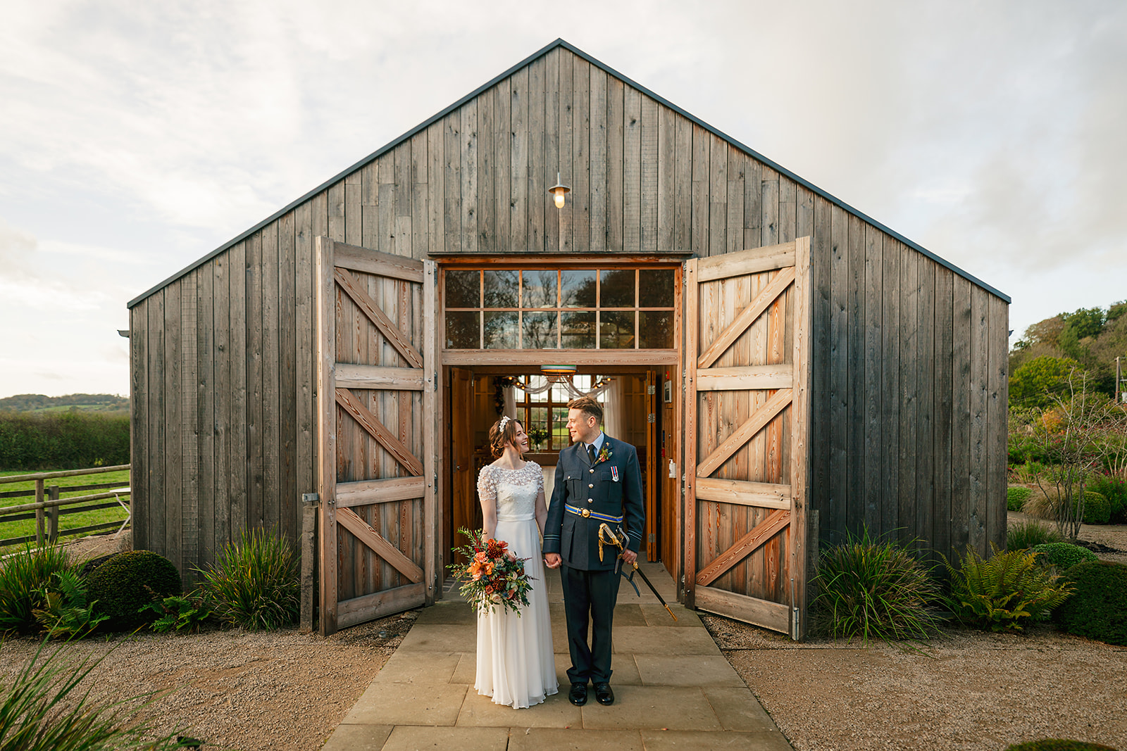 Picture of a groom hugging his bride in front of the barn at Hyde House, cotswolds