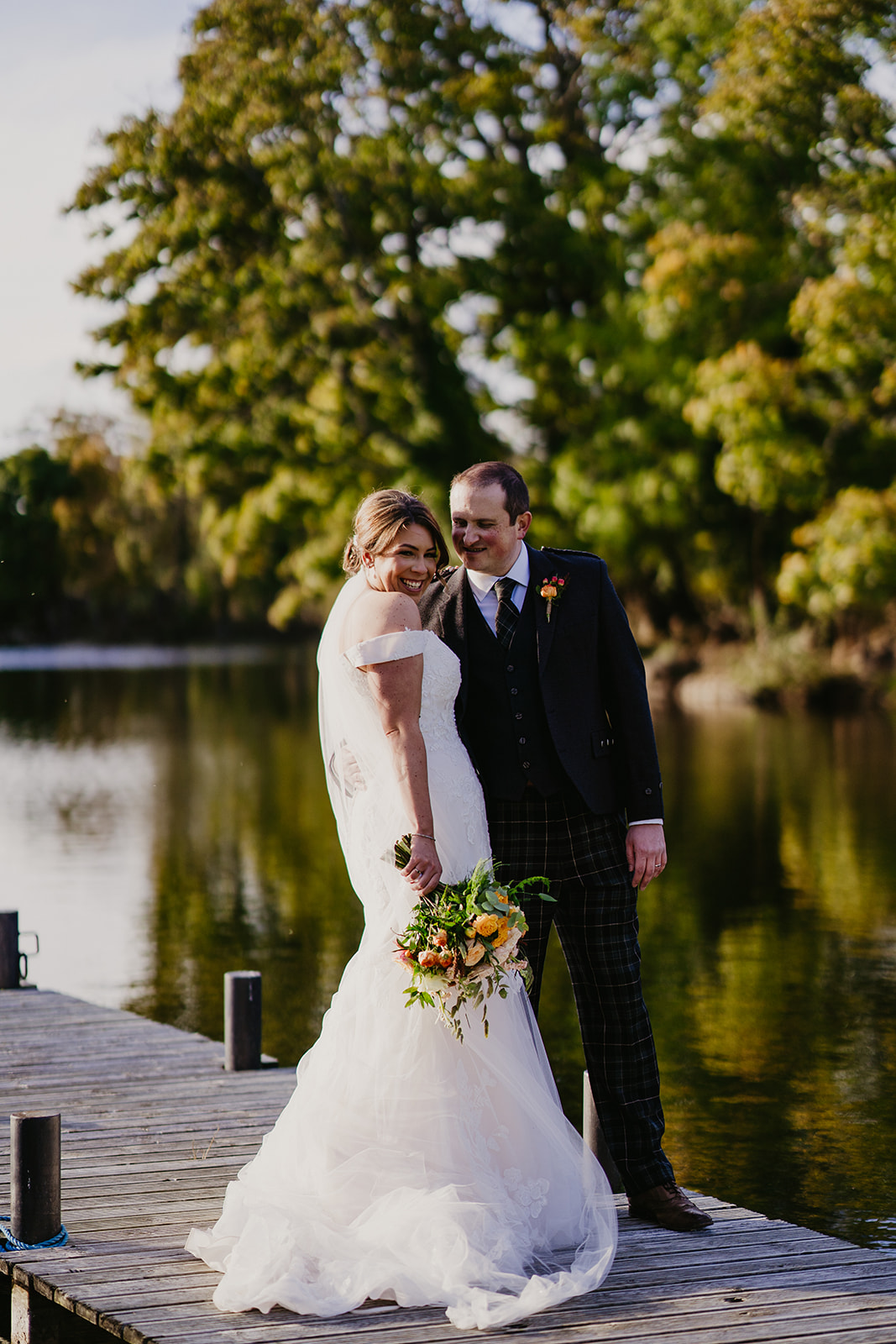 Bride and Groom look over the gorgeous Scottish Loch on their wedding day at Broxmouth Courtyard
