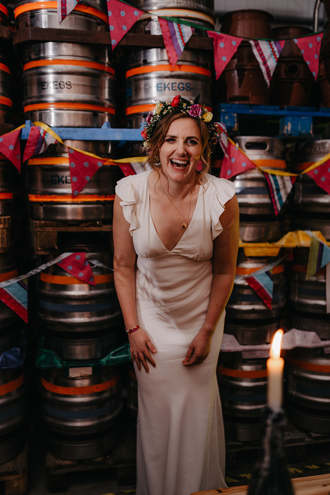 Bride laughs surrounded by kegs at crossborders brewery taproom wedding reception