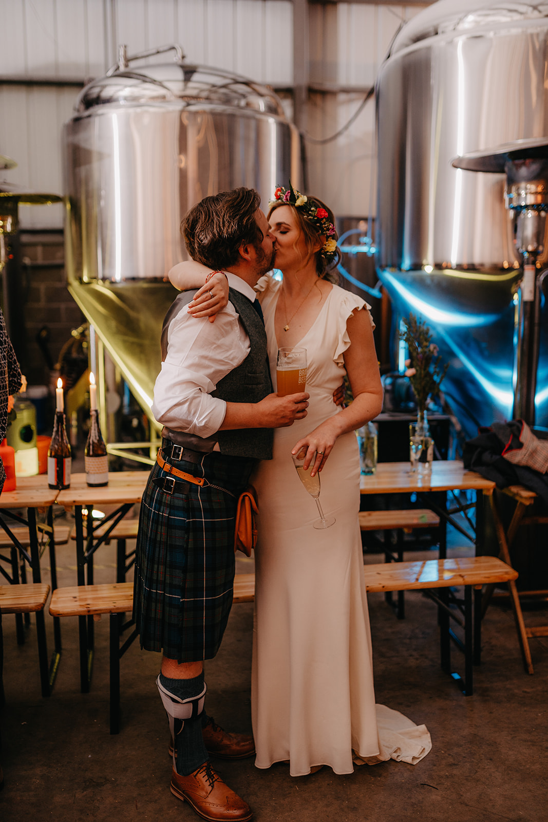 Couple kisssurrounded by kegs at crossborders brewery taproom wedding reception in Edinburgh