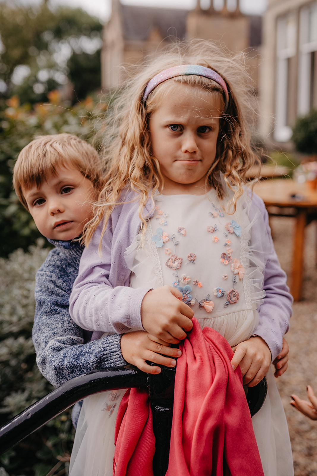 flower girl makes grumpy face with brother behind him 