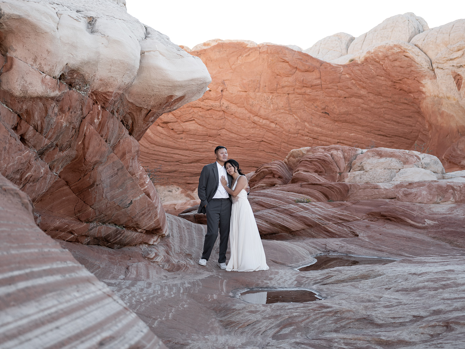 bride and groom standing by Red and white rock formations during their white pocket arizona elopement 