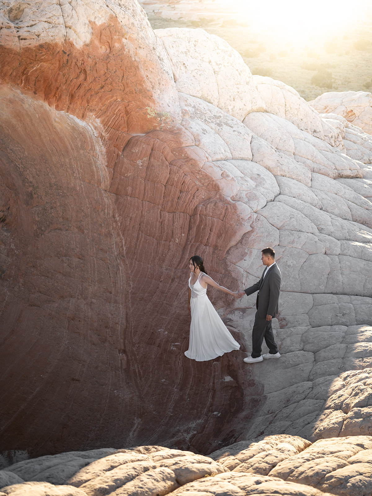 Couple crossing from white rocks to red rocks in White Pocket Arizona during their Elopement 